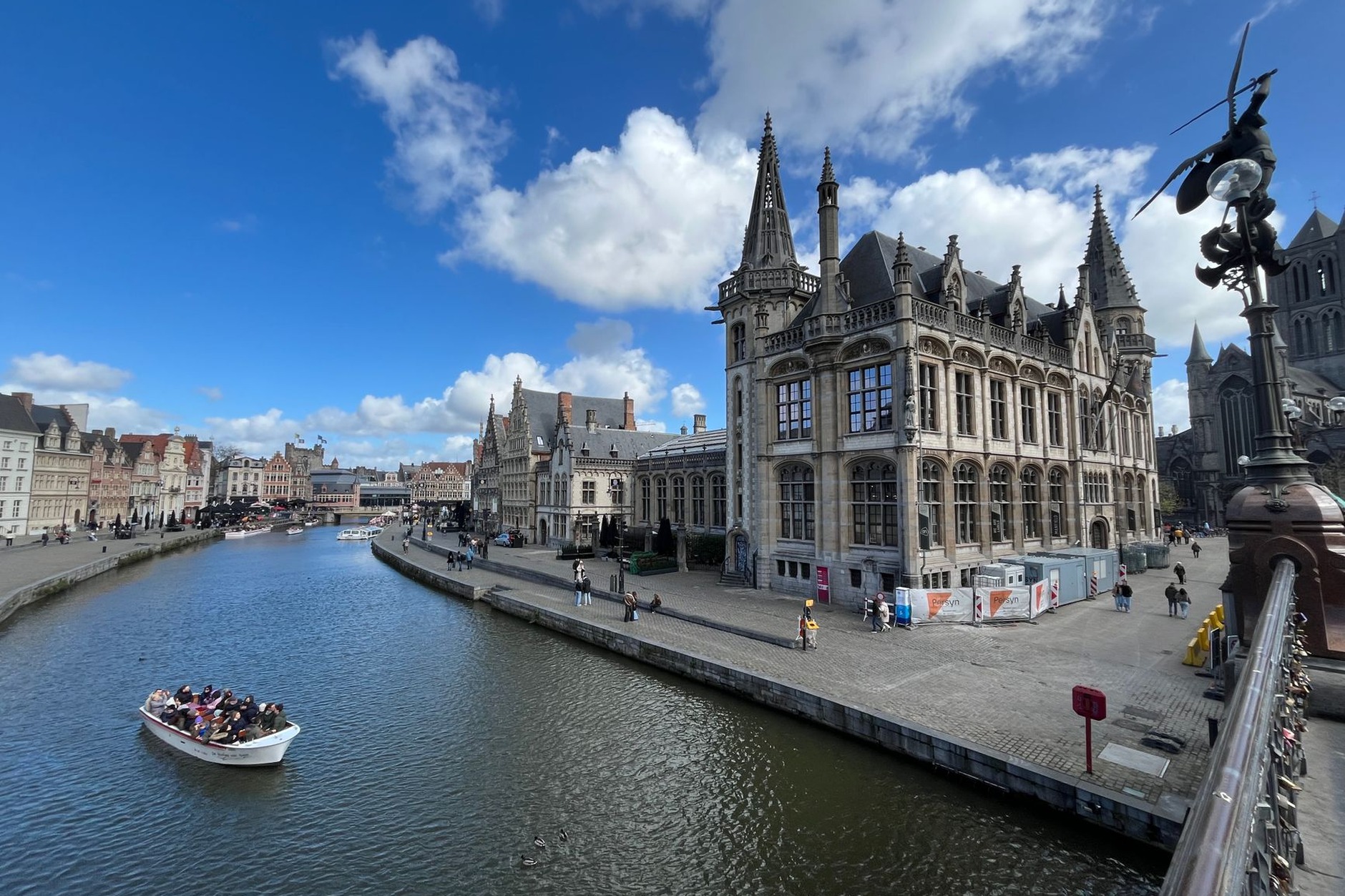 Illuminated medieval guildhouses and historic harbor facades along the Graslei and Korenlei canals in Ghent at dusk