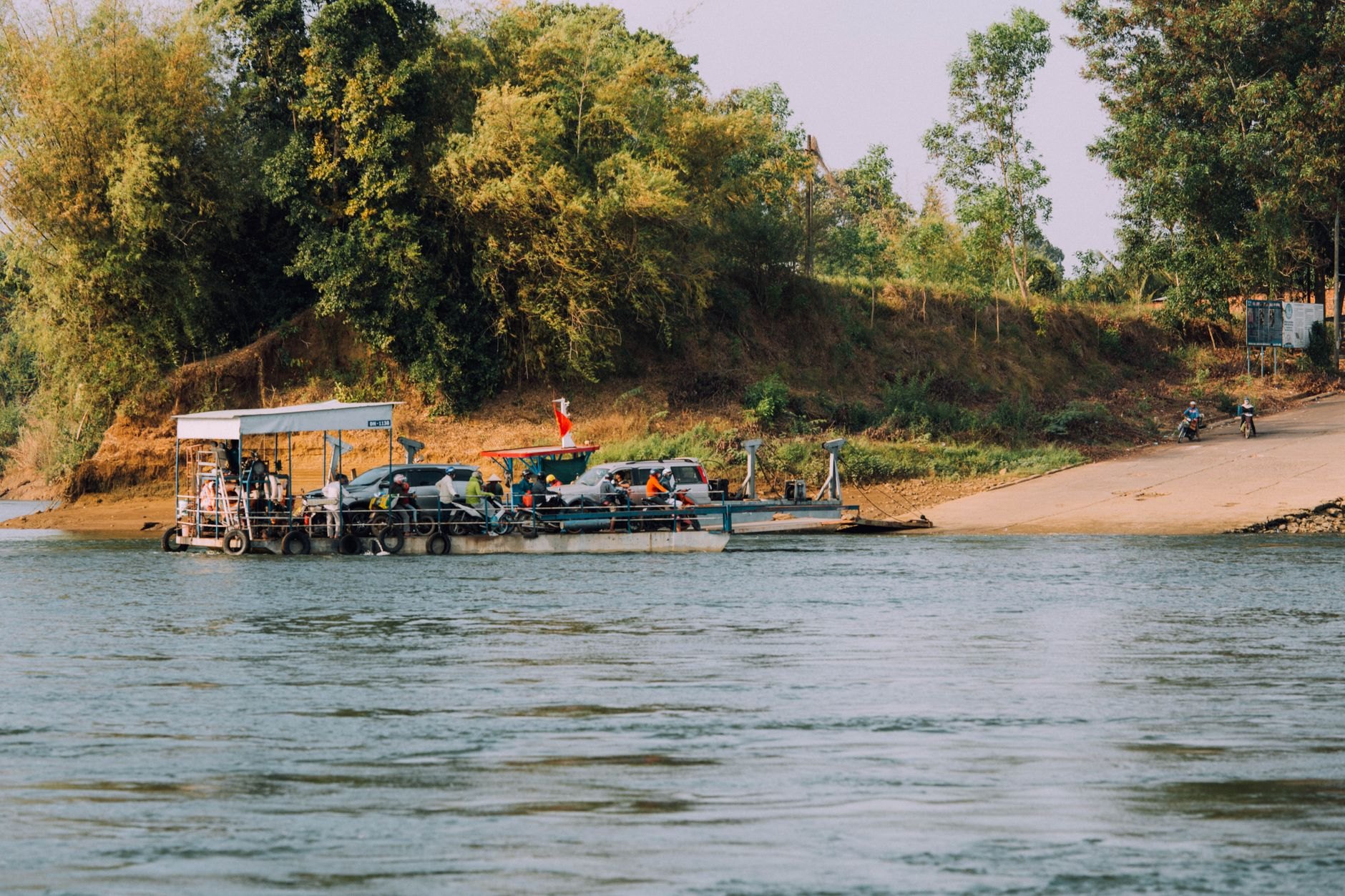 Historic hand-cranked wooden vehicular ferry transporting travellers across the jade-green waters of the Mopan River