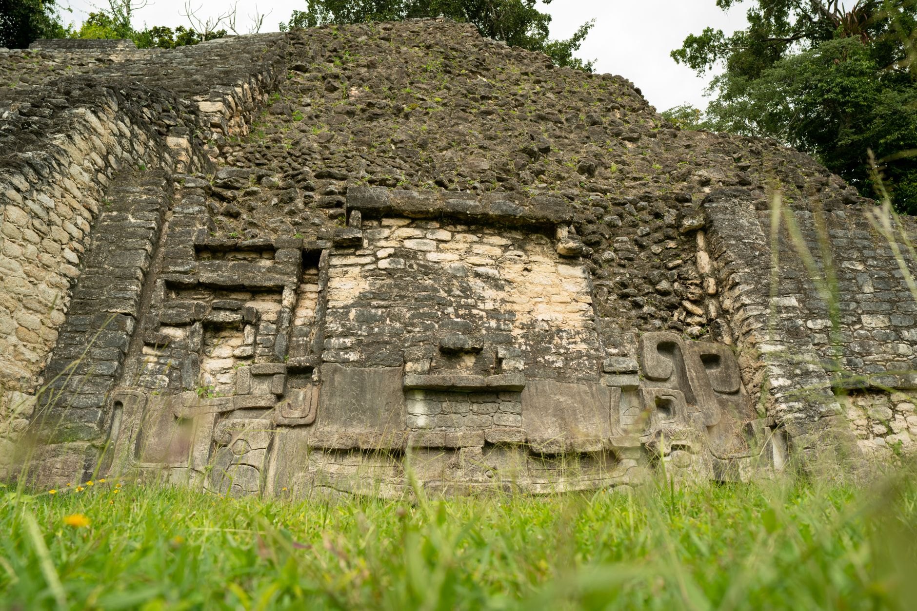 Monumental stone Maya pyramid of El Castillo rising forty meters above dense jungle canopy with carved astronomical friezes