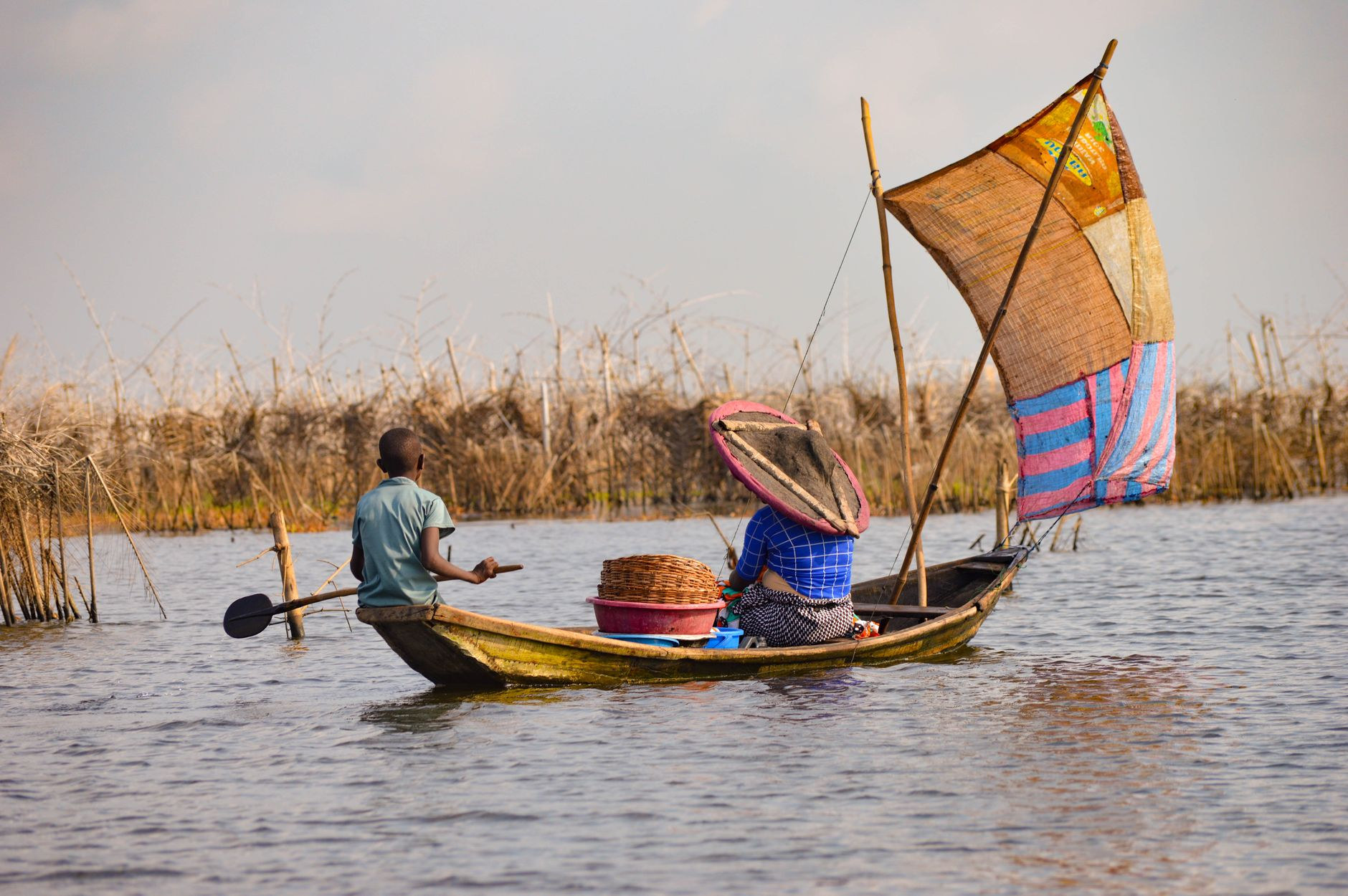 Local residents paddling a traditional wooden pirogue canoe across the calm waters of Lake Nokoue