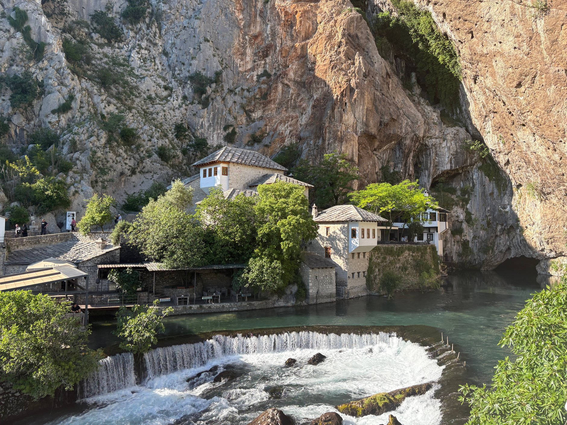 Whitewashed Ottoman Blagaj Tekke dervish monastery built directly into the sheer limestone cliff face beside the emerald Buna spring