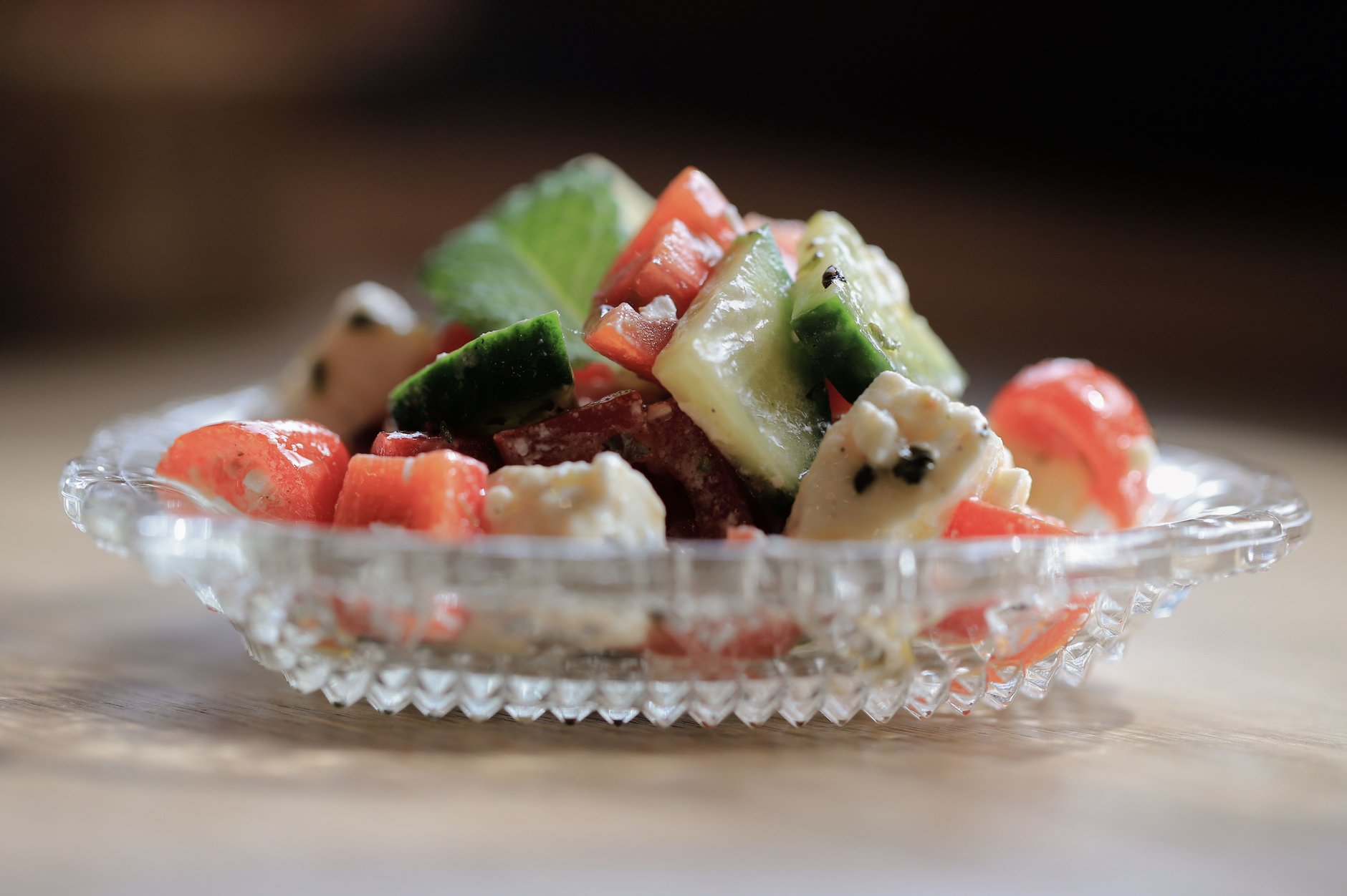 Freshly chopped tomatoes, cucumbers, roasted peppers, and red onions buried beneath grated white sirene cheese