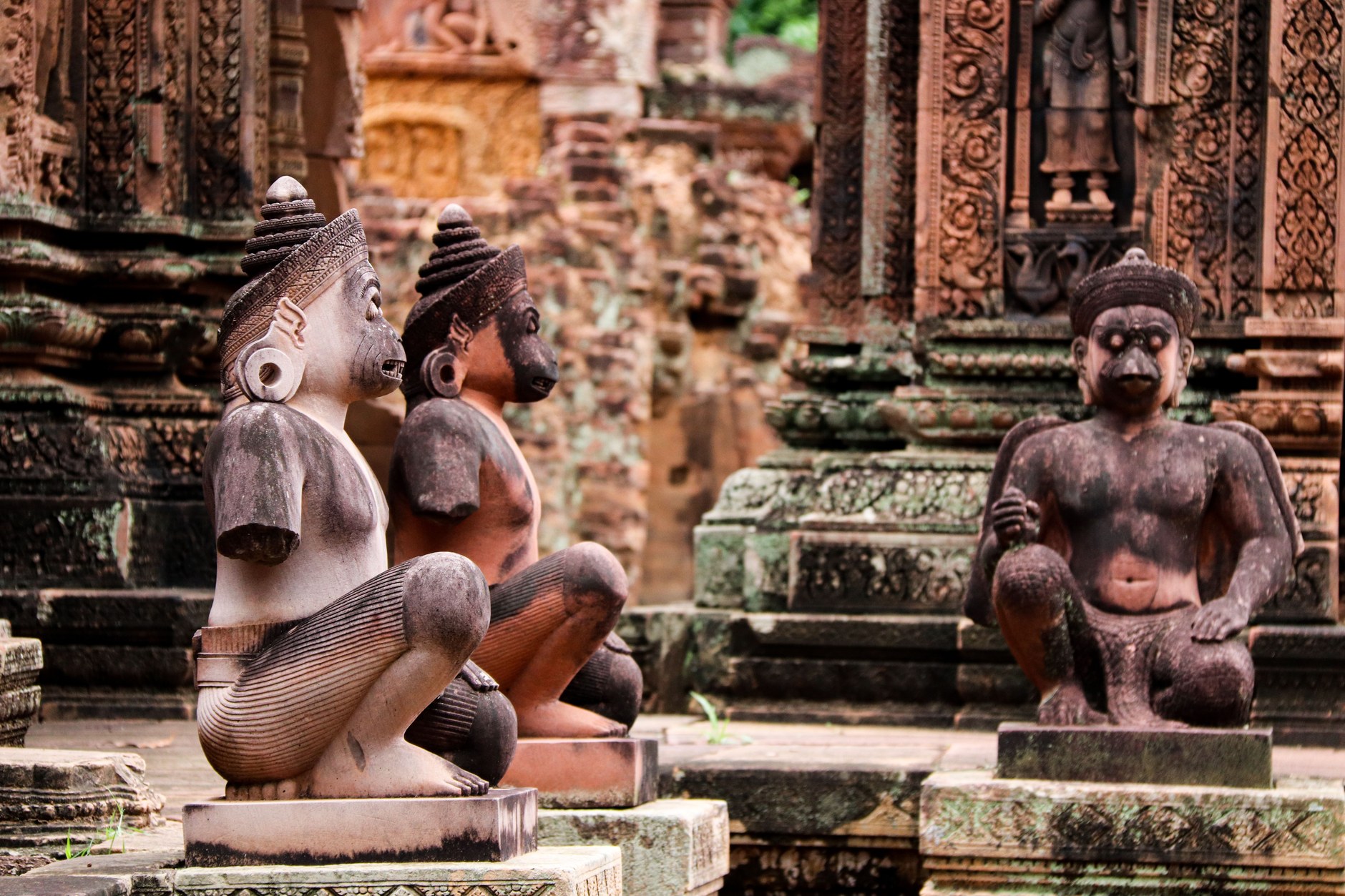 Intricate pink sandstone relief carvings of mythological devatas at Banteay Srei temple