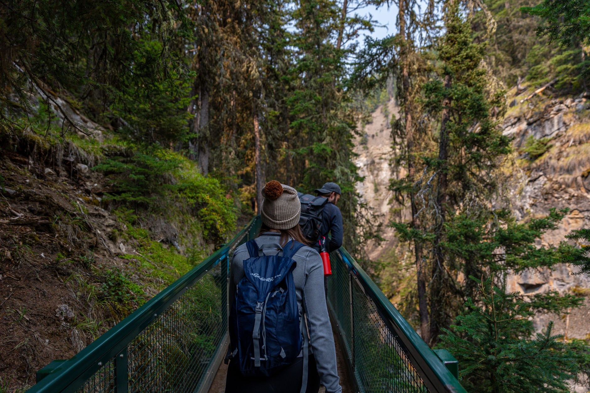 Elevated metal catwalk suspended over rushing waters in Johnston Canyon