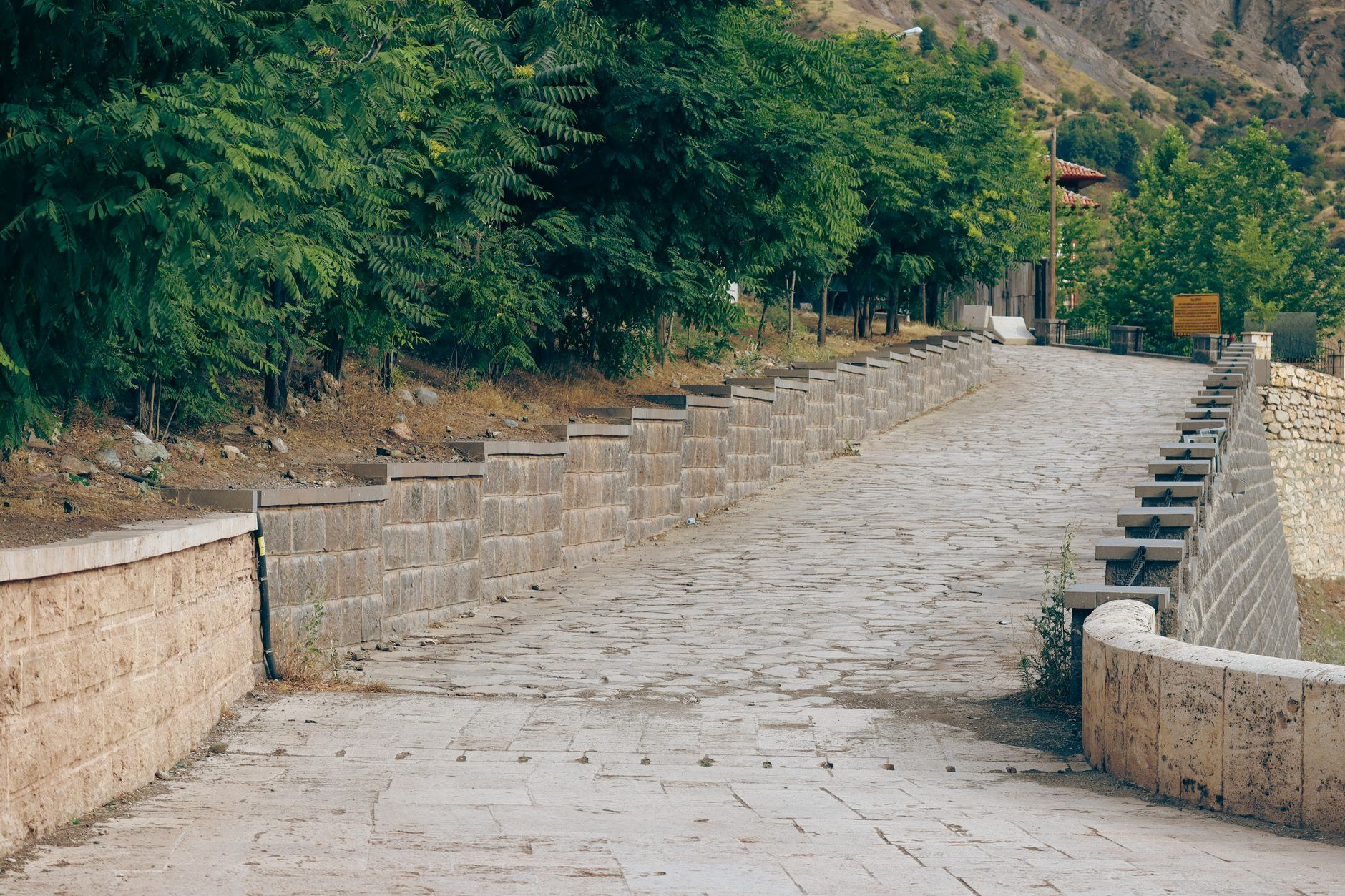 A winding hand-laid basalt cobblestone mountain road climbing through rugged highland peaks