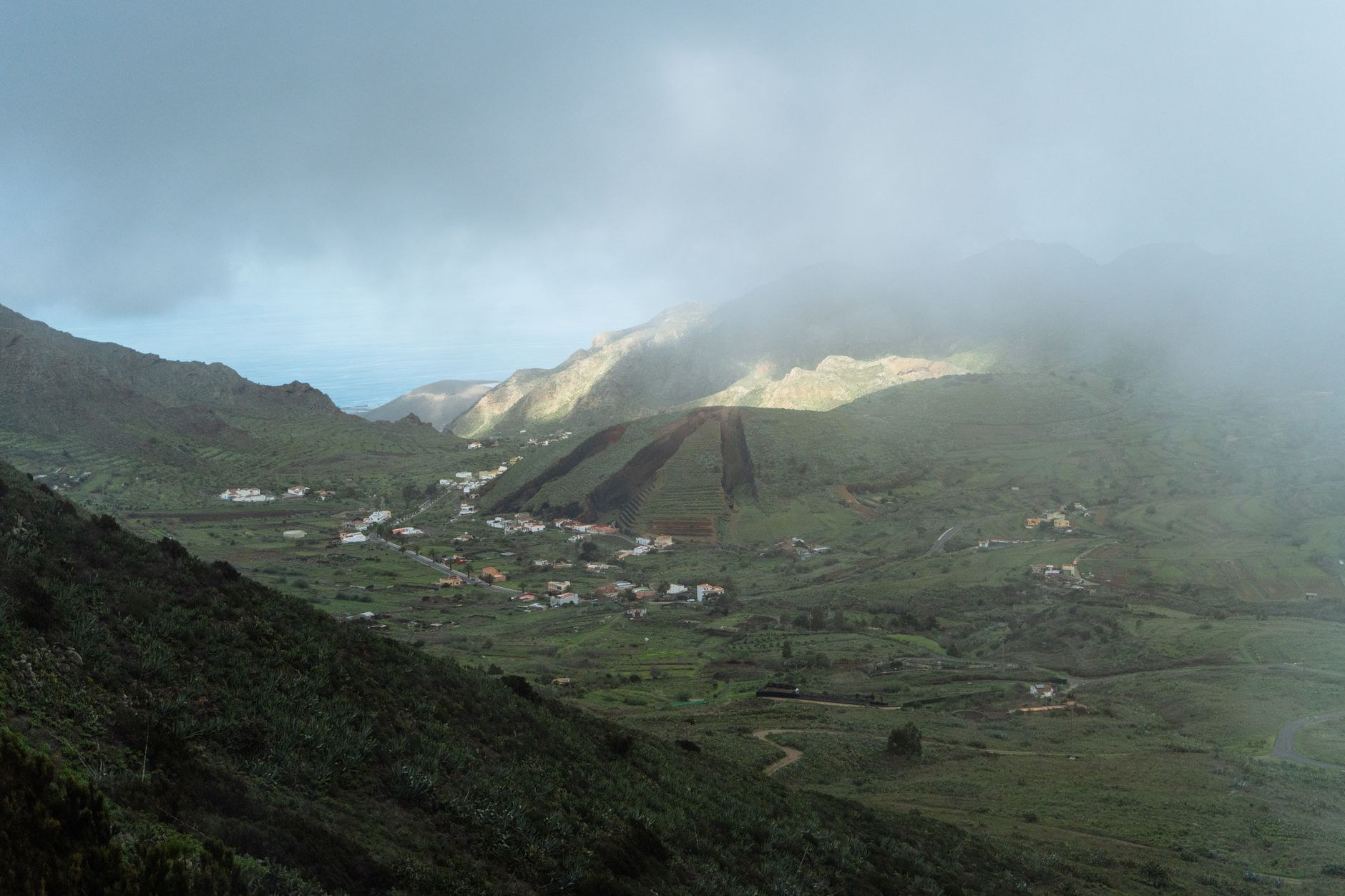 Deep green agricultural mountain valley with steep stone terraces cultivating tropical crops and coffee