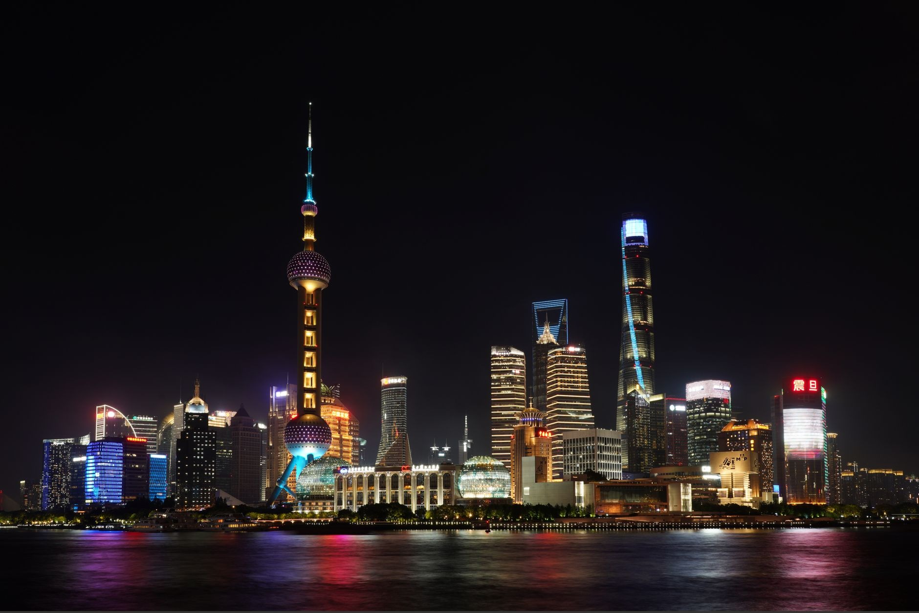Futuristic illuminated skyscrapers of Lujiazui in Pudong reflecting across the Huangpu River viewed from The Bund in Shanghai