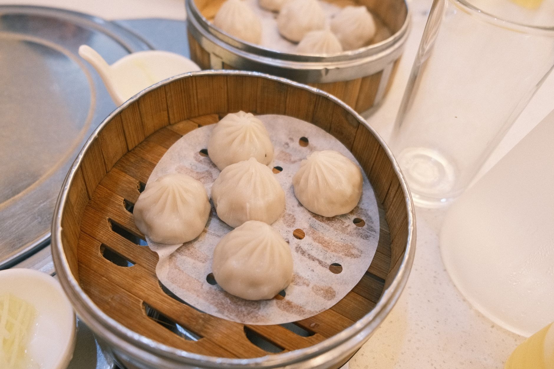 Steaming bamboo basket filled with delicate freshly folded Shanghai soup dumplings xiaolongbao and black vinegar dip