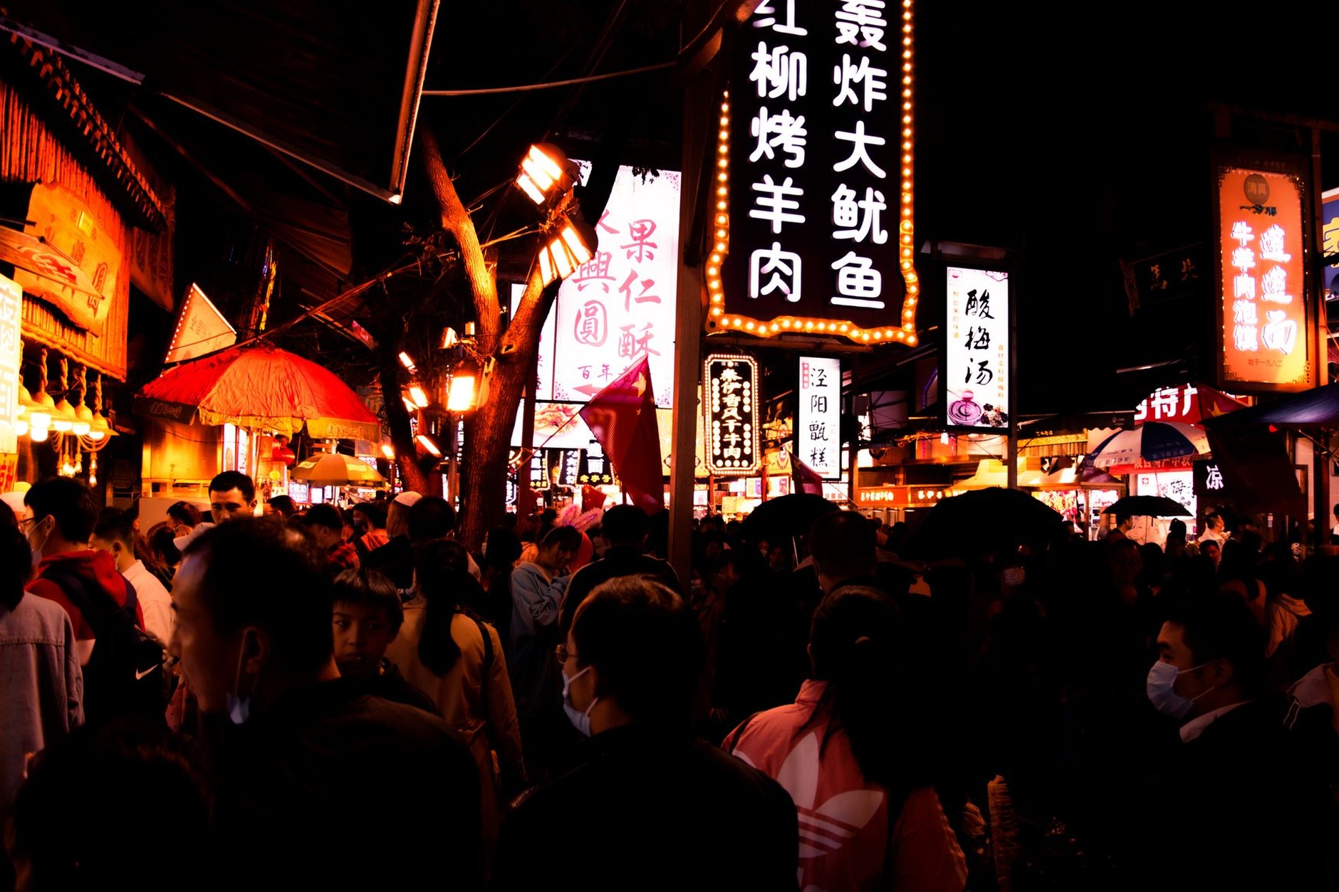 Vibrant night market street lined with glowing red lanterns and sizzling halal food stalls in Xi'an's historic Muslim Quarter