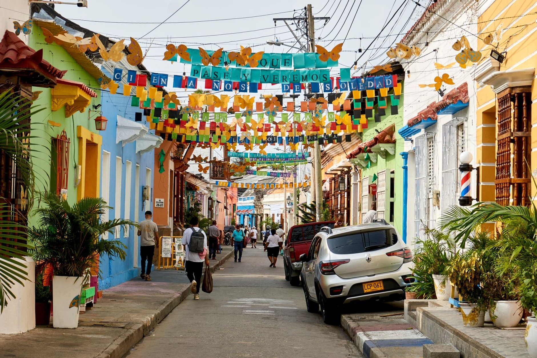 Vibrant street art murals and decorative hanging umbrellas shading a lively pedestrian alley in Cartagena's bohemian Getsemaní neighborhood