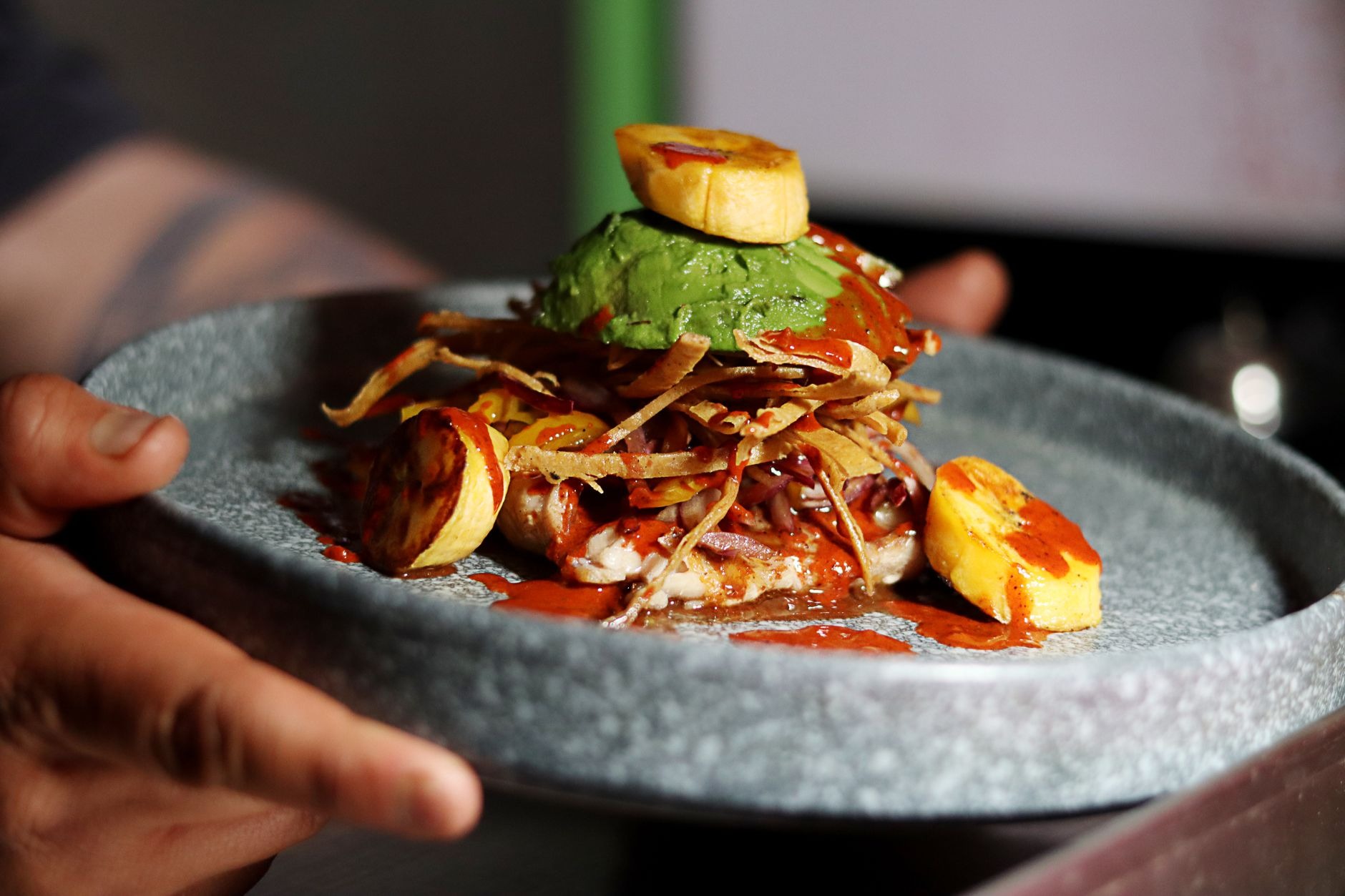 Generous Colombian bandeja paisa platter featuring crispy chicharrón, grilled beef, fried egg, red beans, rice, plantain, and avocado