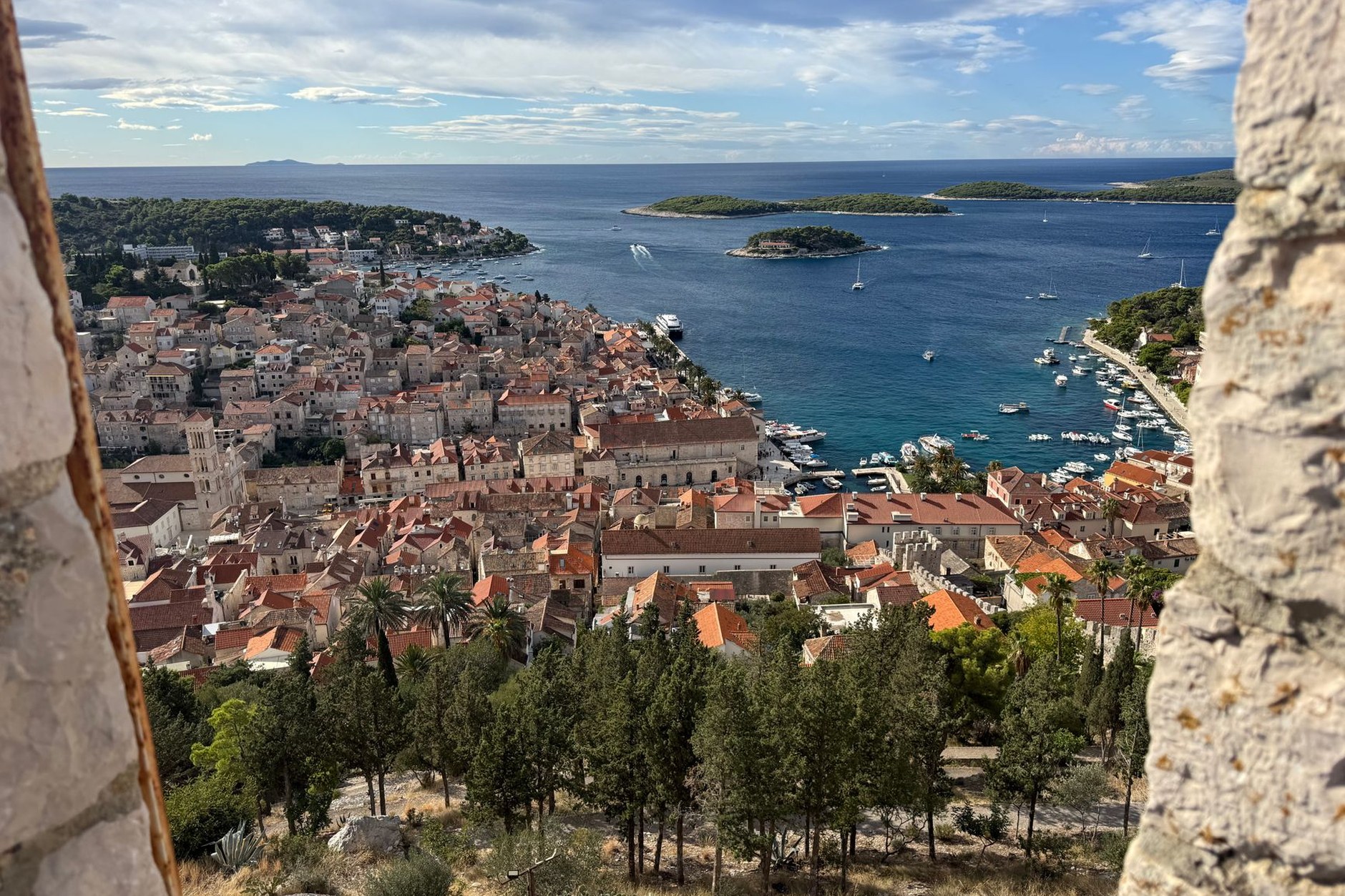 Hvar Town harbor lined with palm trees, yachts, and limestone Venetian stone buildings