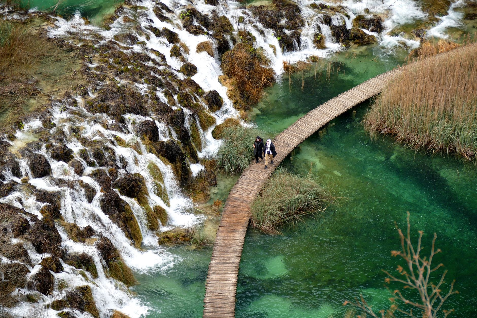 Wooden pedestrian boardwalk winding across turquoise terraced lakes and cascading waterfalls