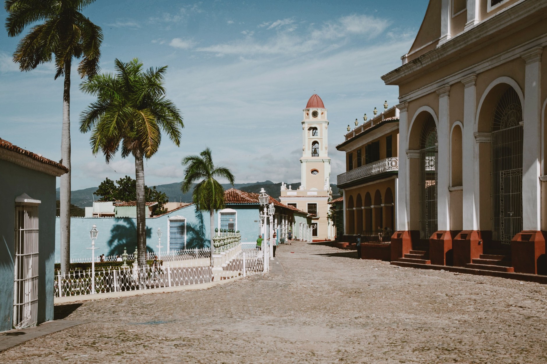 Colonial cobblestone street lined with pastel painted houses leading toward the bell tower in Trinidad