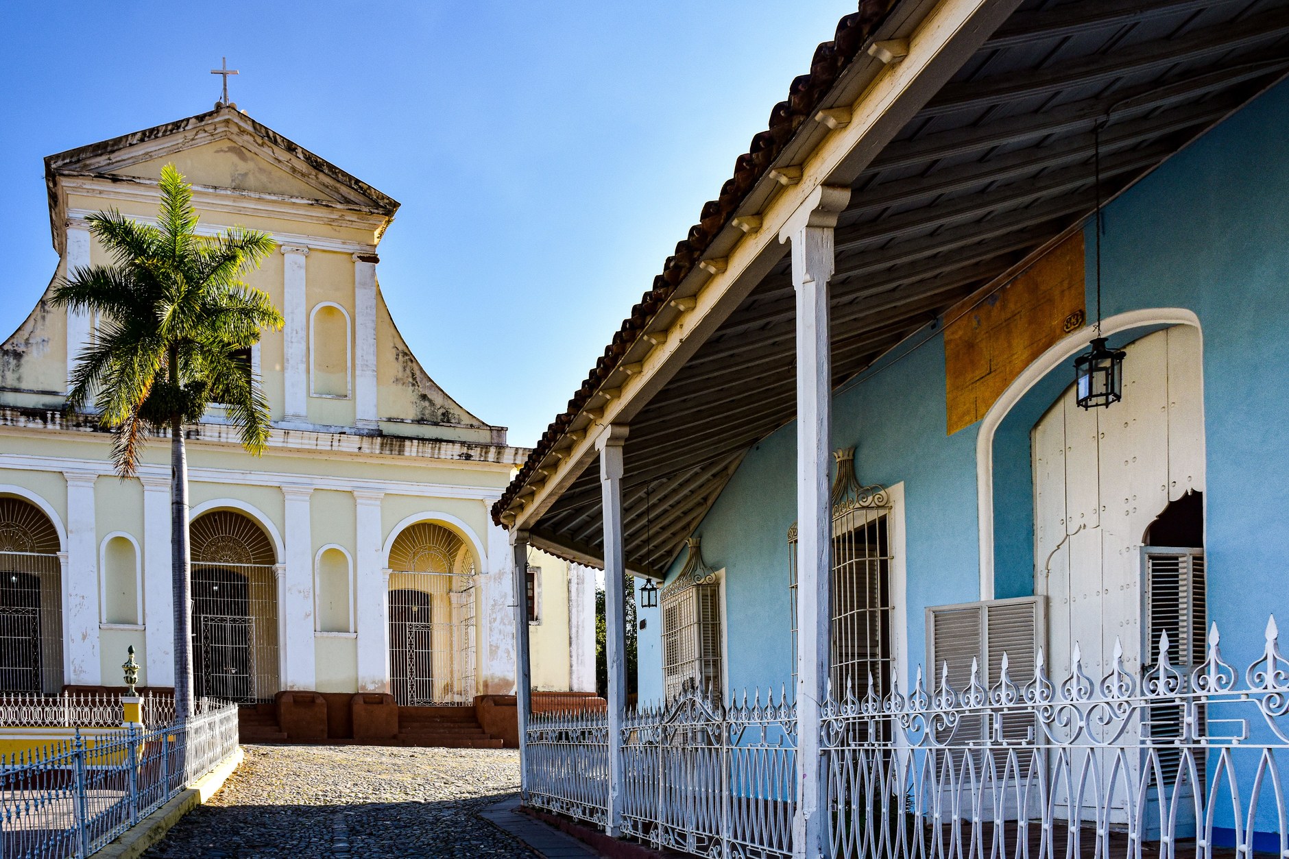 Historic Plaza Mayor in Trinidad with yellow colonial buildings and the Church of the Holy Trinity
