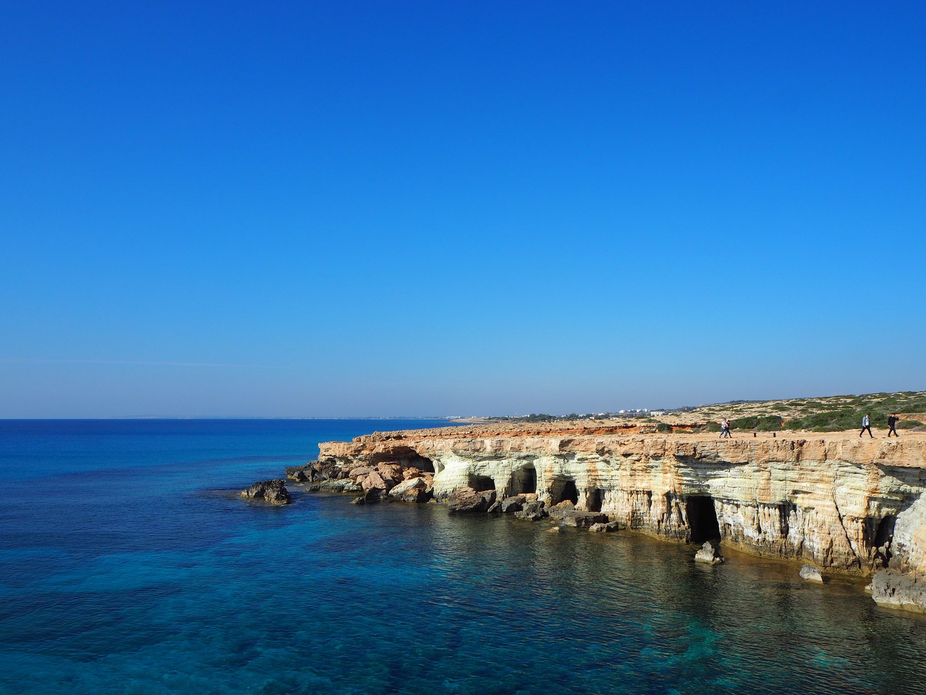 Carved natural limestone sea caves and clear turquoise Mediterranean water along the coastal headland of Cape Greko