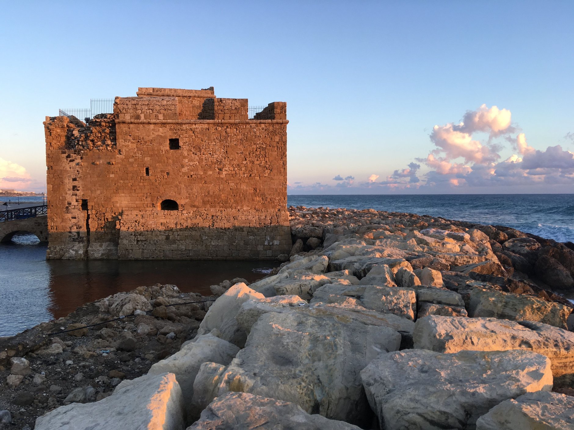 Medieval stone fortress of Paphos Castle standing at the edge of the harbor basin with fishing boats moored nearby