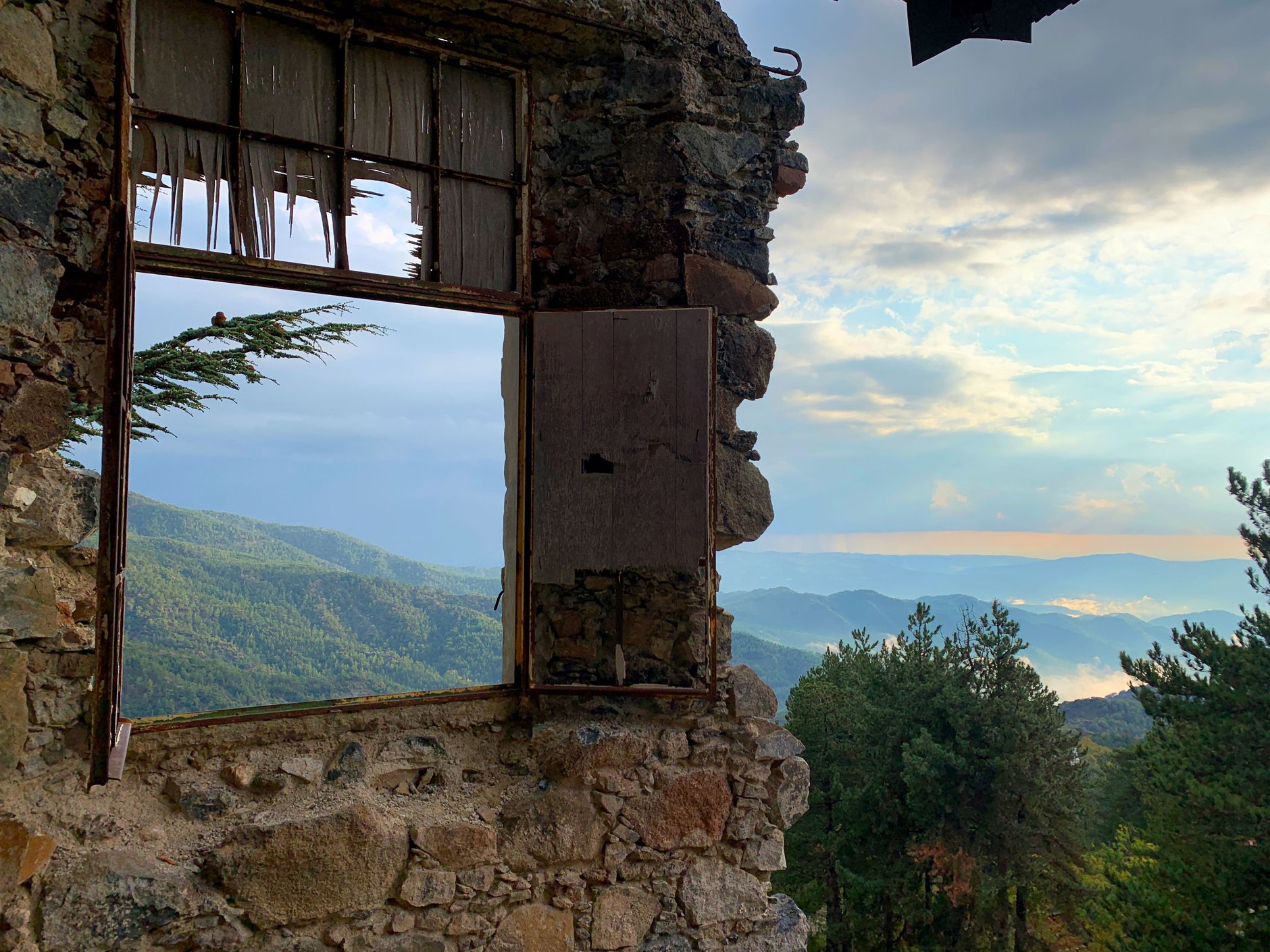 Traditional stone houses with terracotta tile roofs clustered among pine-covered slopes and terraced vineyards in the Troodos mountains