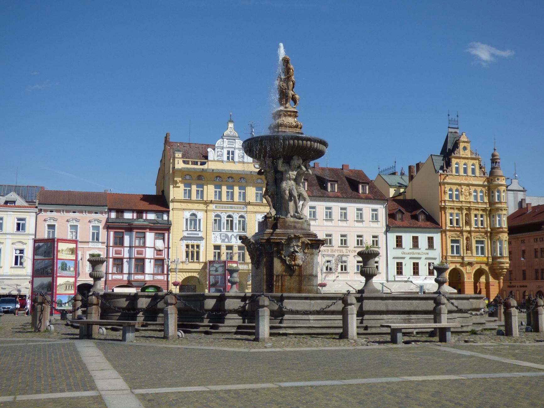 Sprawling square paved with stone slabs bordered by arcaded pastel baroque facades and Samson's Fountain