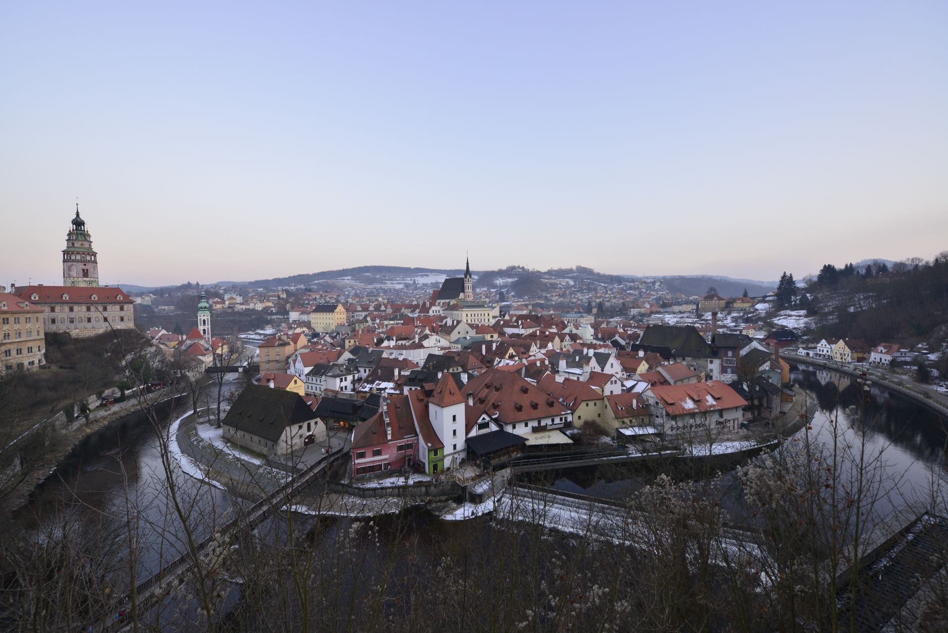 Pink Renaissance castle tower of Český Krumlov rising above red tile roofs and the loop of the Vltava River