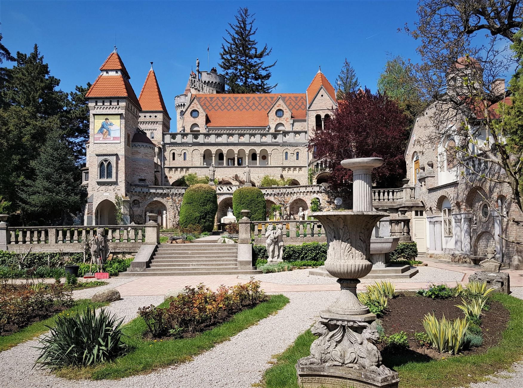 Intricate white battlements, crenellated towers, and landscaped royal gardens of neo-Gothic Hluboká Castle