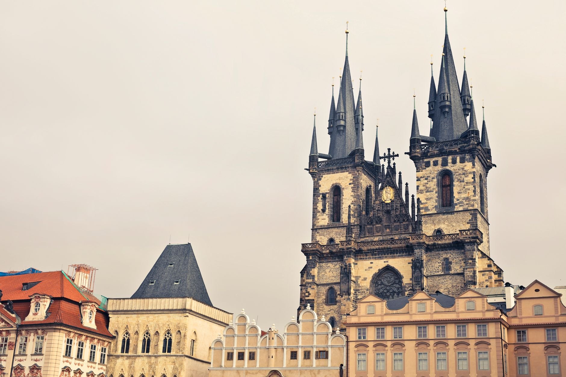 Cobblestones of Prague Old Town Square bordered by pastel Renaissance palaces and the twin Gothic towers of Týn Church