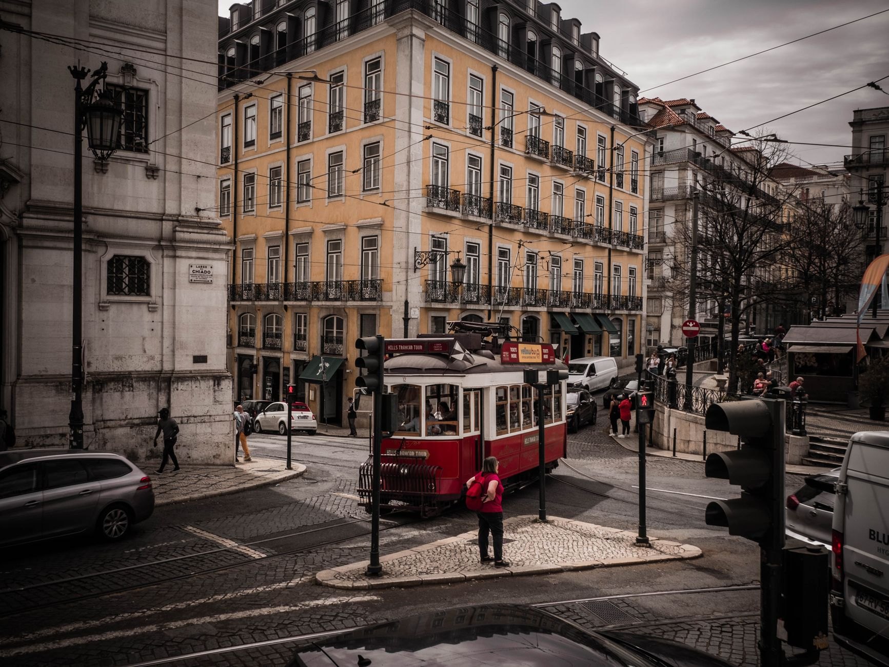 Classic red Prague tram gliding along a curved cobblestone street past baroque buildings in Malá Strana