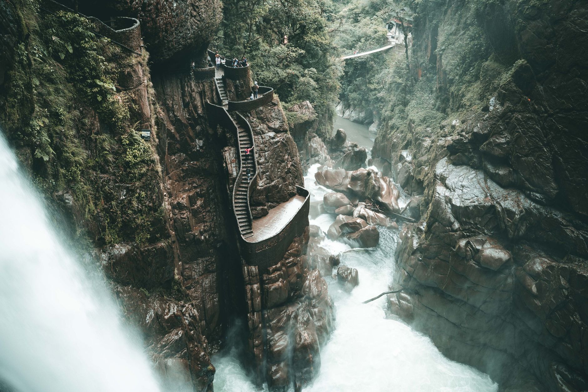Rushing torrent of Pailón del Diablo waterfall crashing through a lush tropical gorge in Baños Ecuador