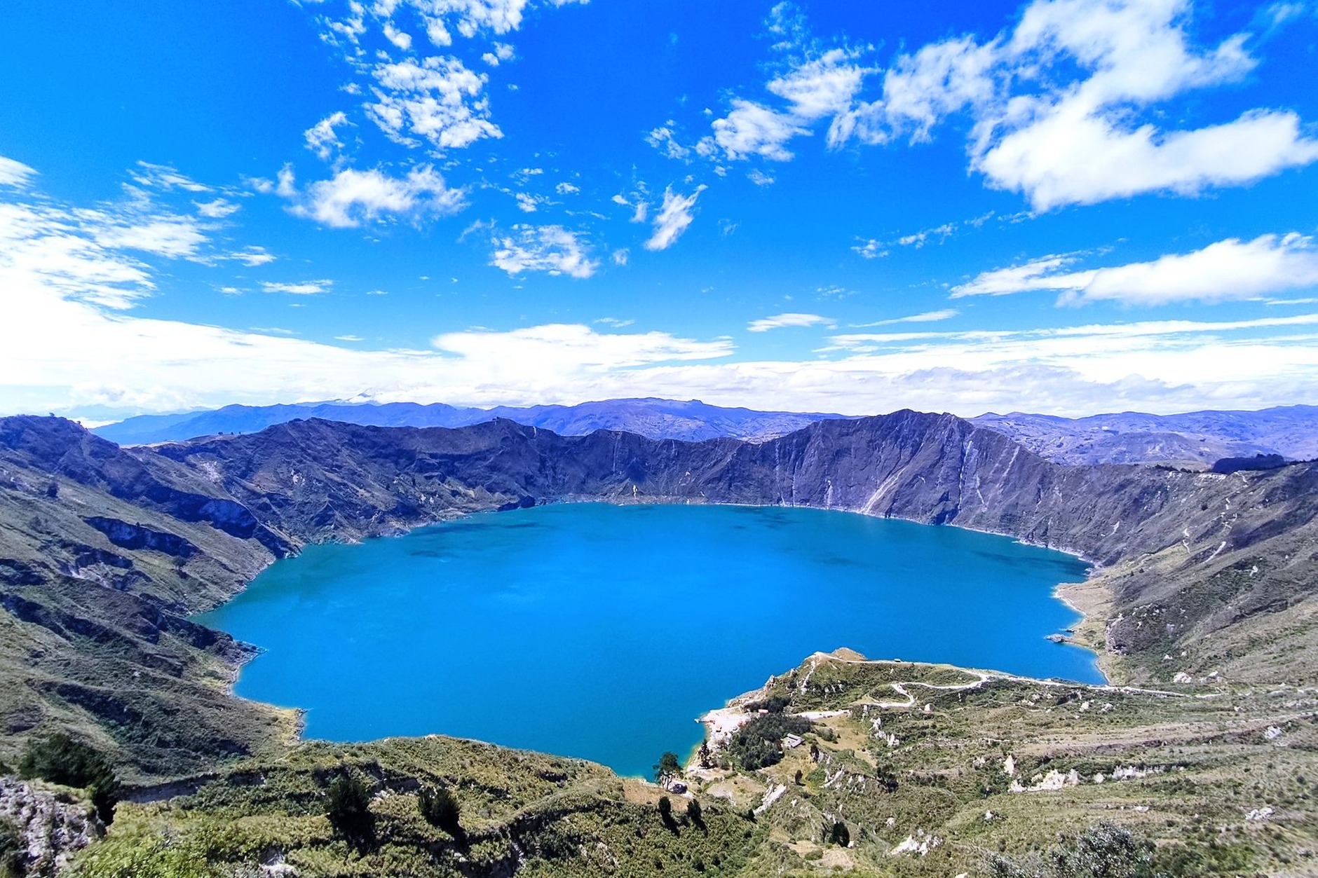 Breathtaking emerald green waters of Quilotoa volcanic crater lake surrounded by jagged high mountain peaks