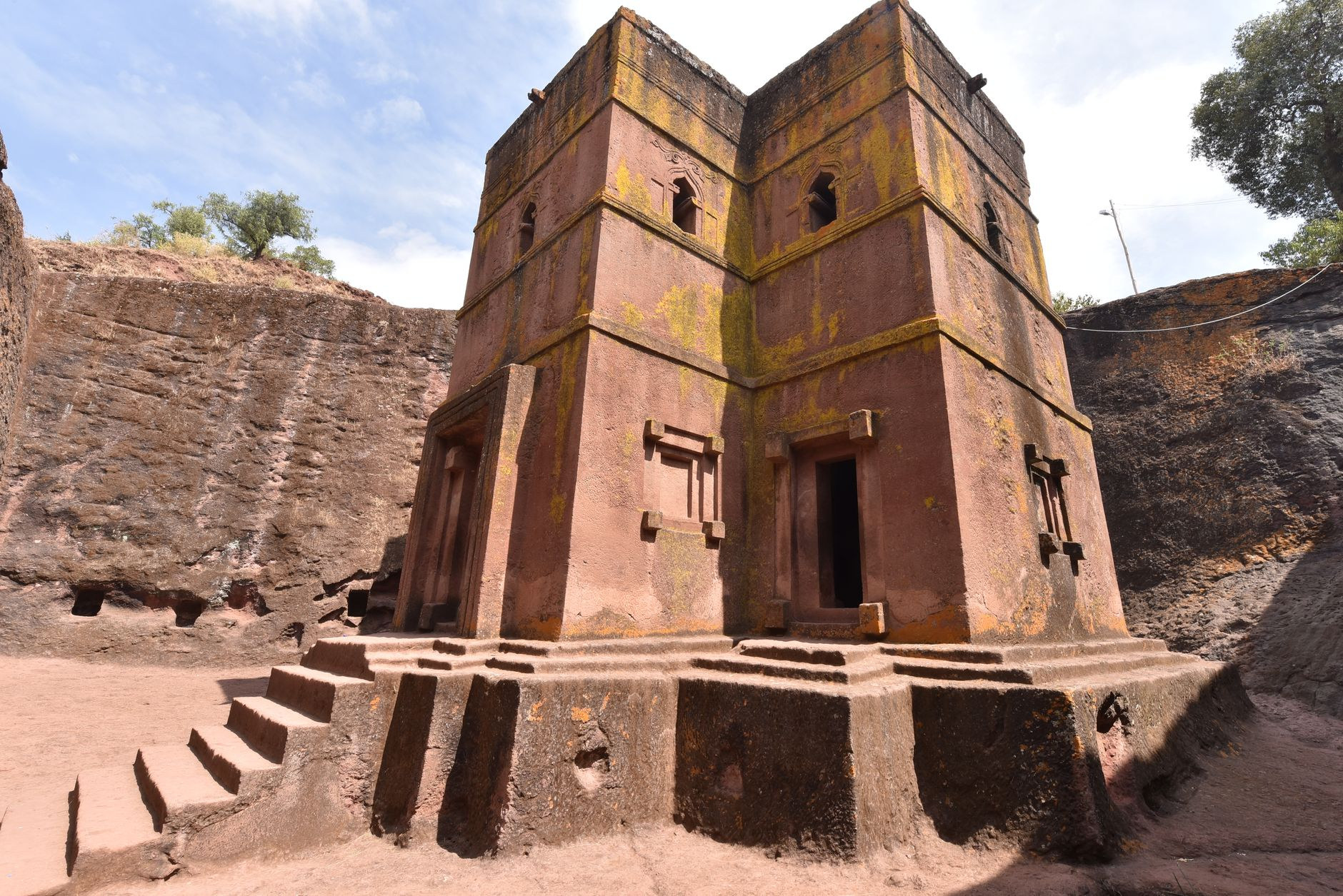 Detailed exterior view of the monolithic rock-cut facade of Bet Giyorgis surrounded by deep excavated stone trenches