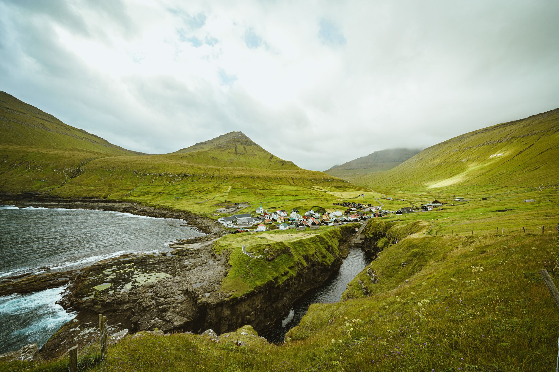Nordic coastal village with colorful timber houses overlooking a deep natural sea cleft canyon