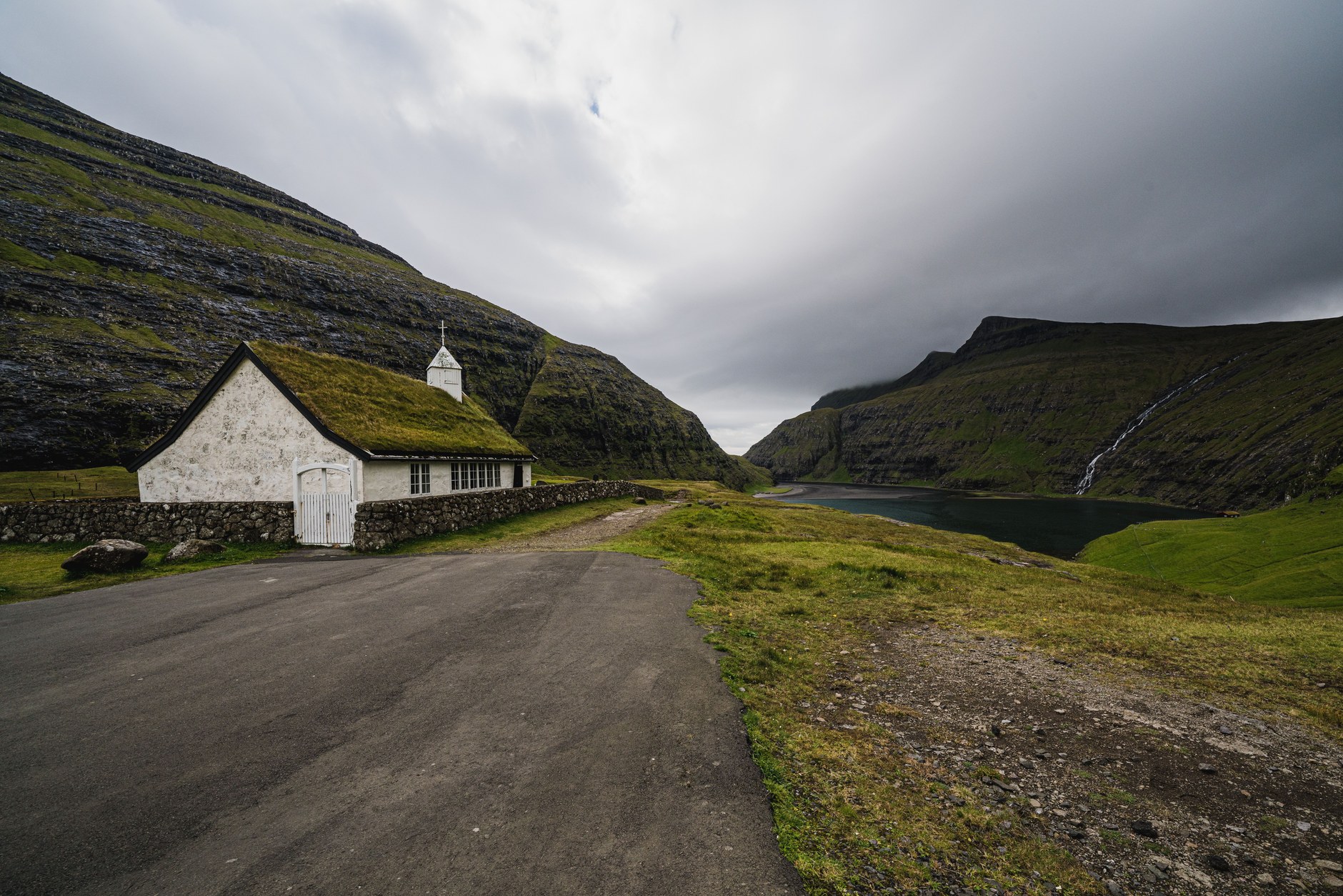 Traditional white church with a living green grass turf roof in a green amphitheater valley in Saksun