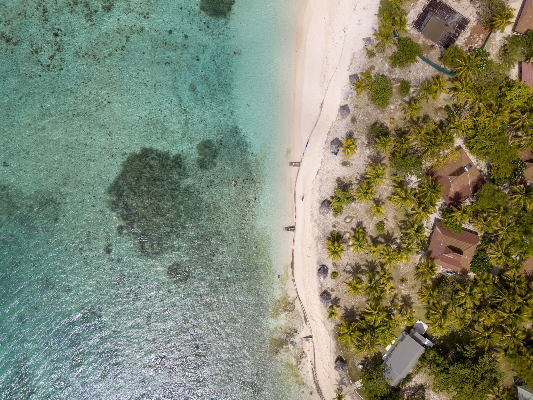 Aerial view of a tiny coral sand atoll in the Mamanuca Islands surrounded by concentric turquoise reef formations