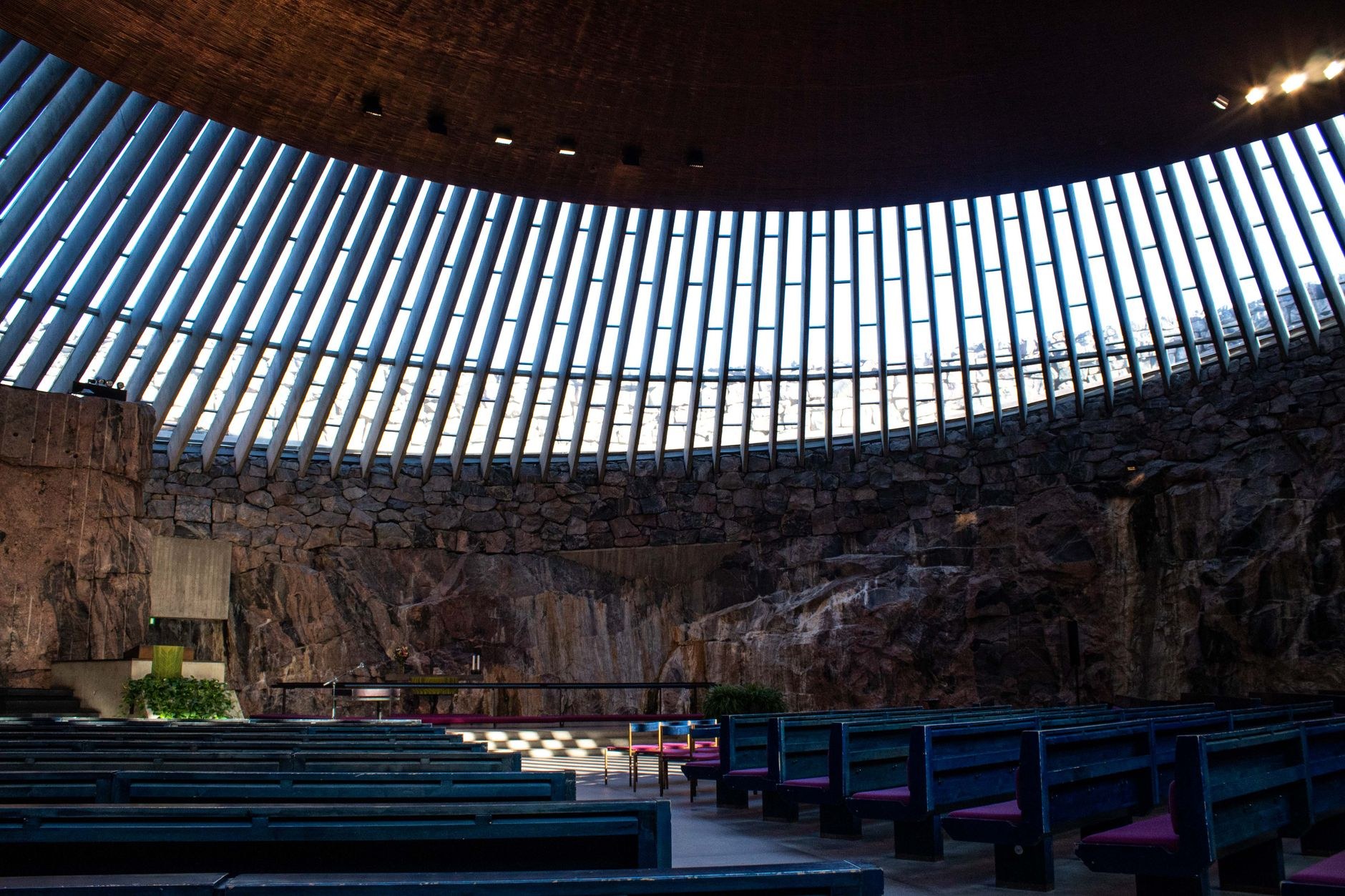 Dramatic copper-domed ceiling and exposed rough granite bedrock interior of Temppeliaukio Rock Church in Helsinki