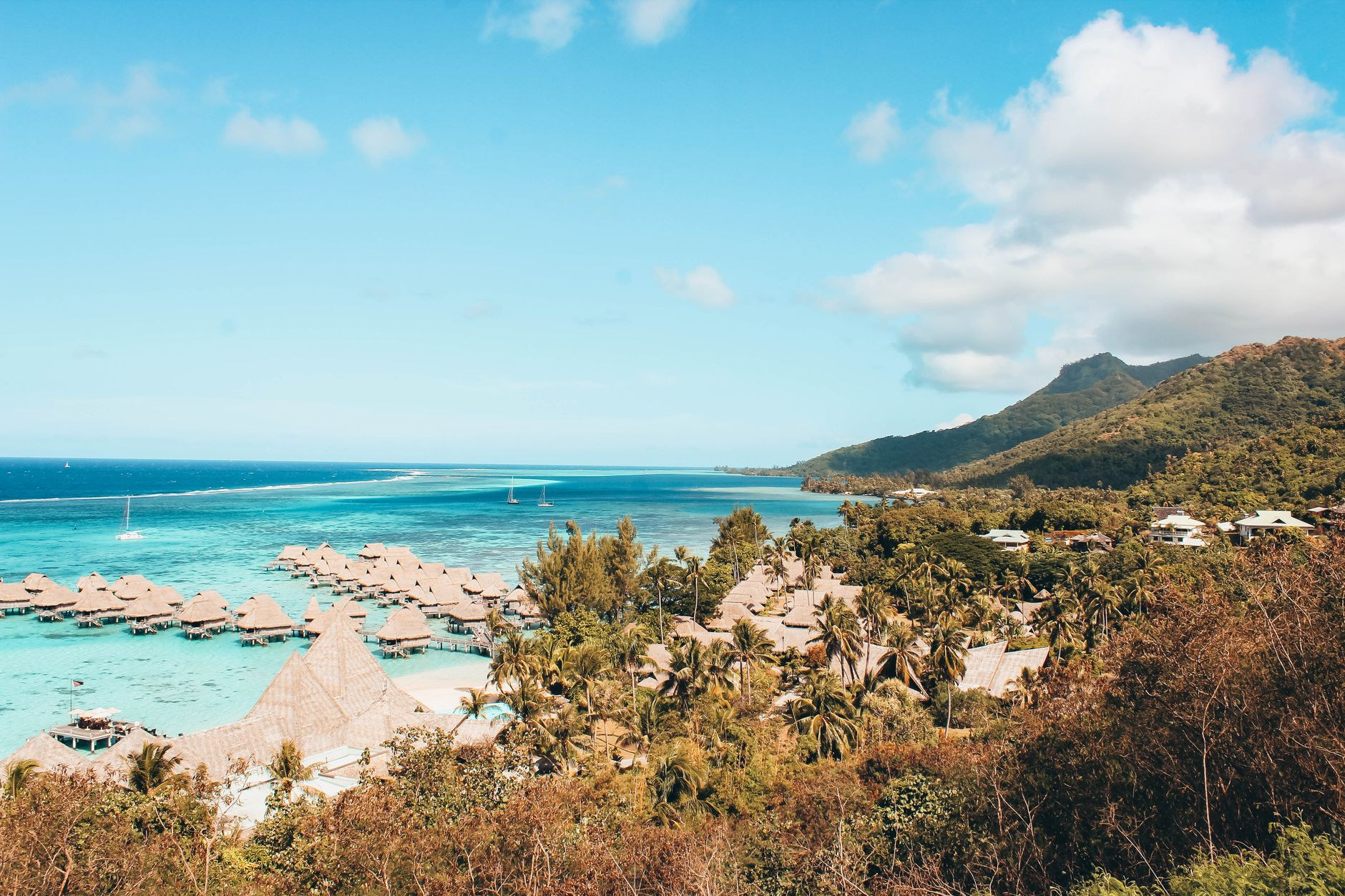 Traditional thatched overwater bungalows built on wooden stilts over a crystal clear turquoise lagoon