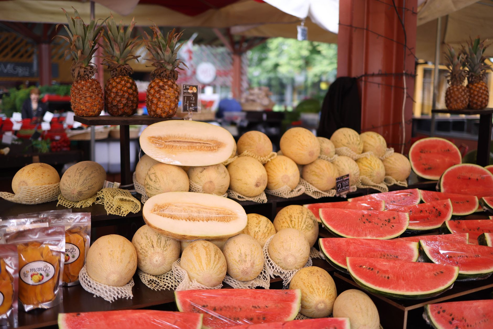 Fresh tropical melons, pineapples, and island produce arranged at a covered market stall in French Polynesia