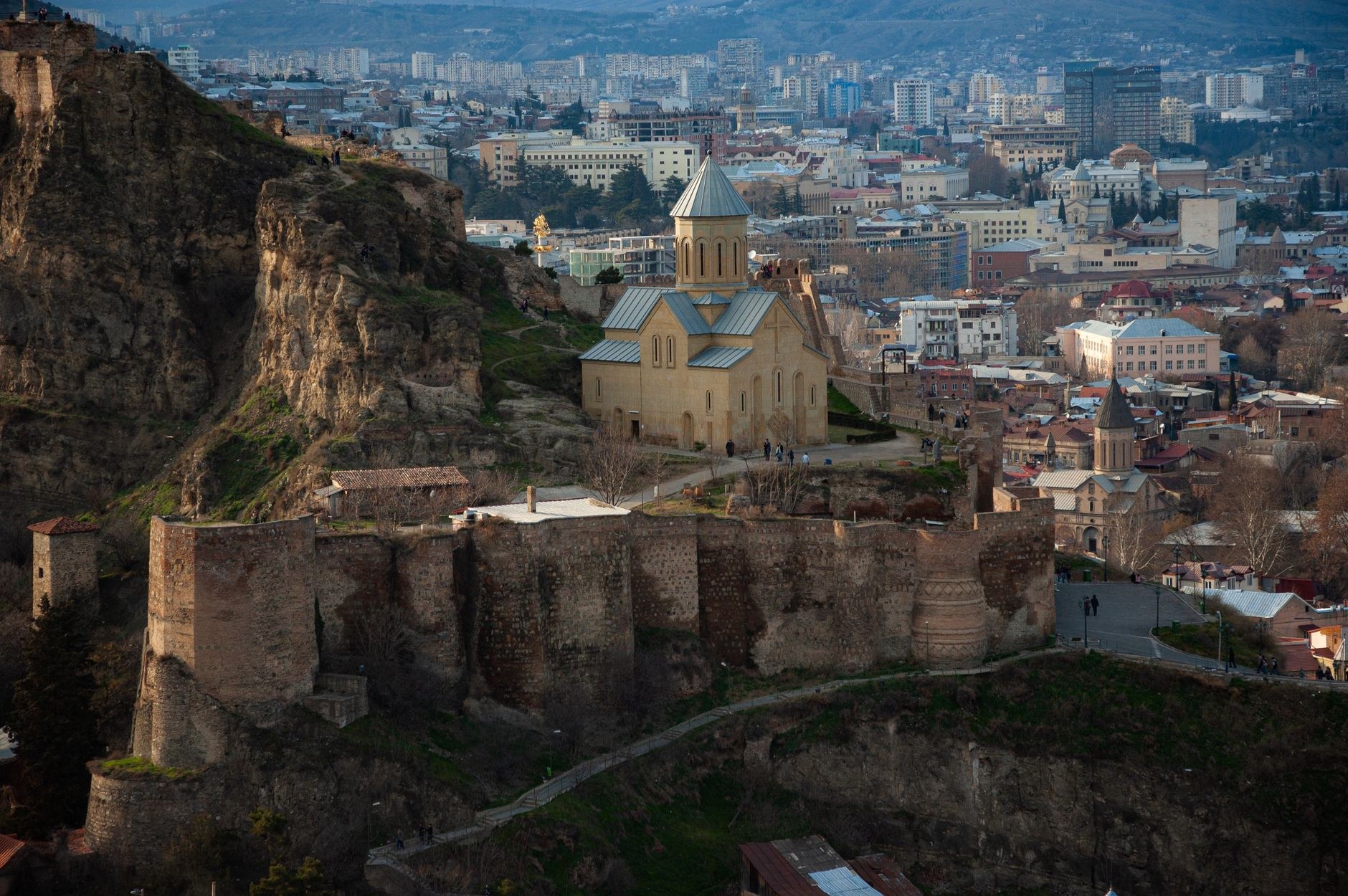 Brick domed roofs of the historic Abanotubani sulfur bathhouses beneath the ancient ramparts of Narikala Fortress in Tbilisi