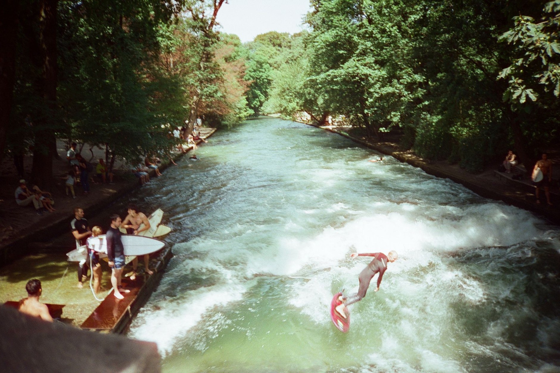 River surfers riding the continuous standing wave on Munich's Eisbachwelle