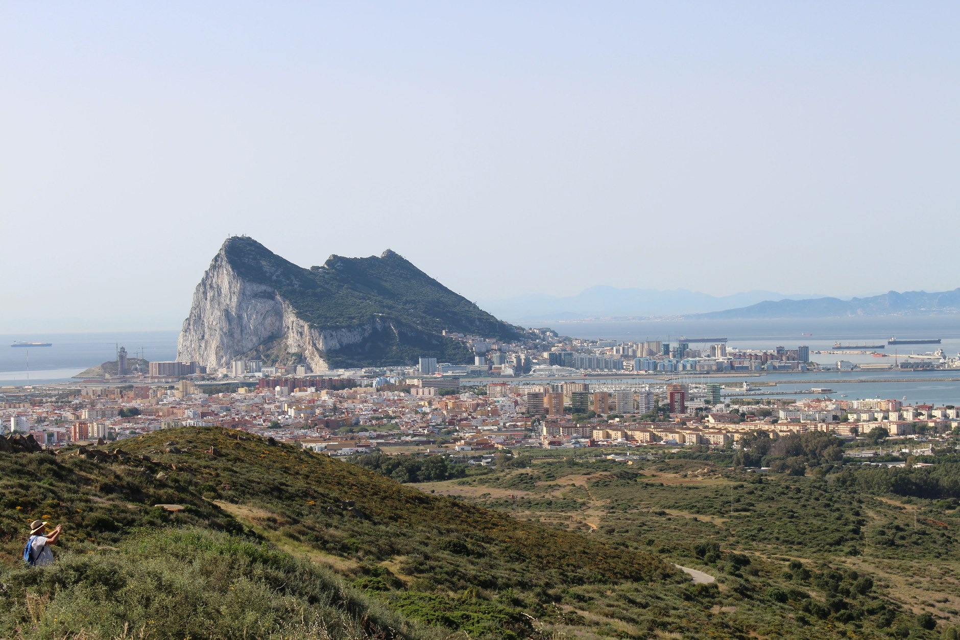 The Rock of Gibraltar dominating the skyline above coastal town buildings and blue waters of the bay