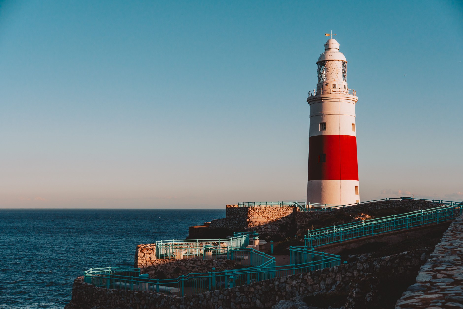 Red and white painted Trinity Lighthouse at Europa Point standing against the blue waters of the Strait of Gibraltar