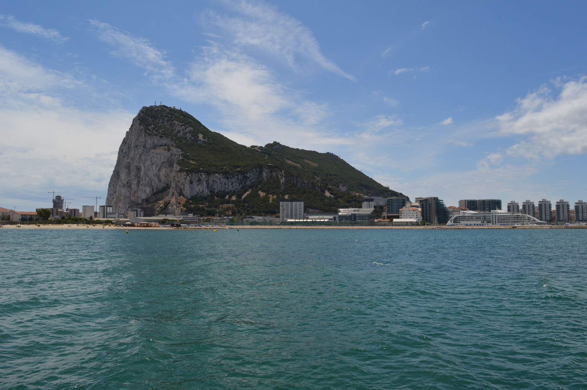 Waterfront buildings and marina quays with the massive limestone Rock of Gibraltar rising in the background