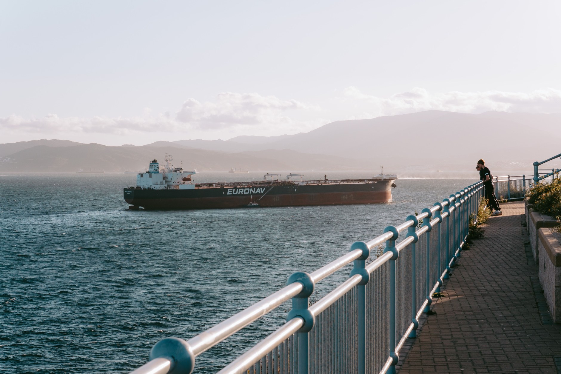 Cargo vessel transiting through the Strait of Gibraltar with the silhouette of the African coastline in the distance