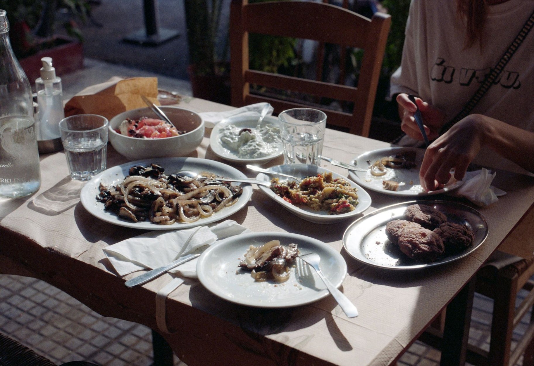Traditional Greek salad with thick feta block, olives, and fresh bread on a rustic table