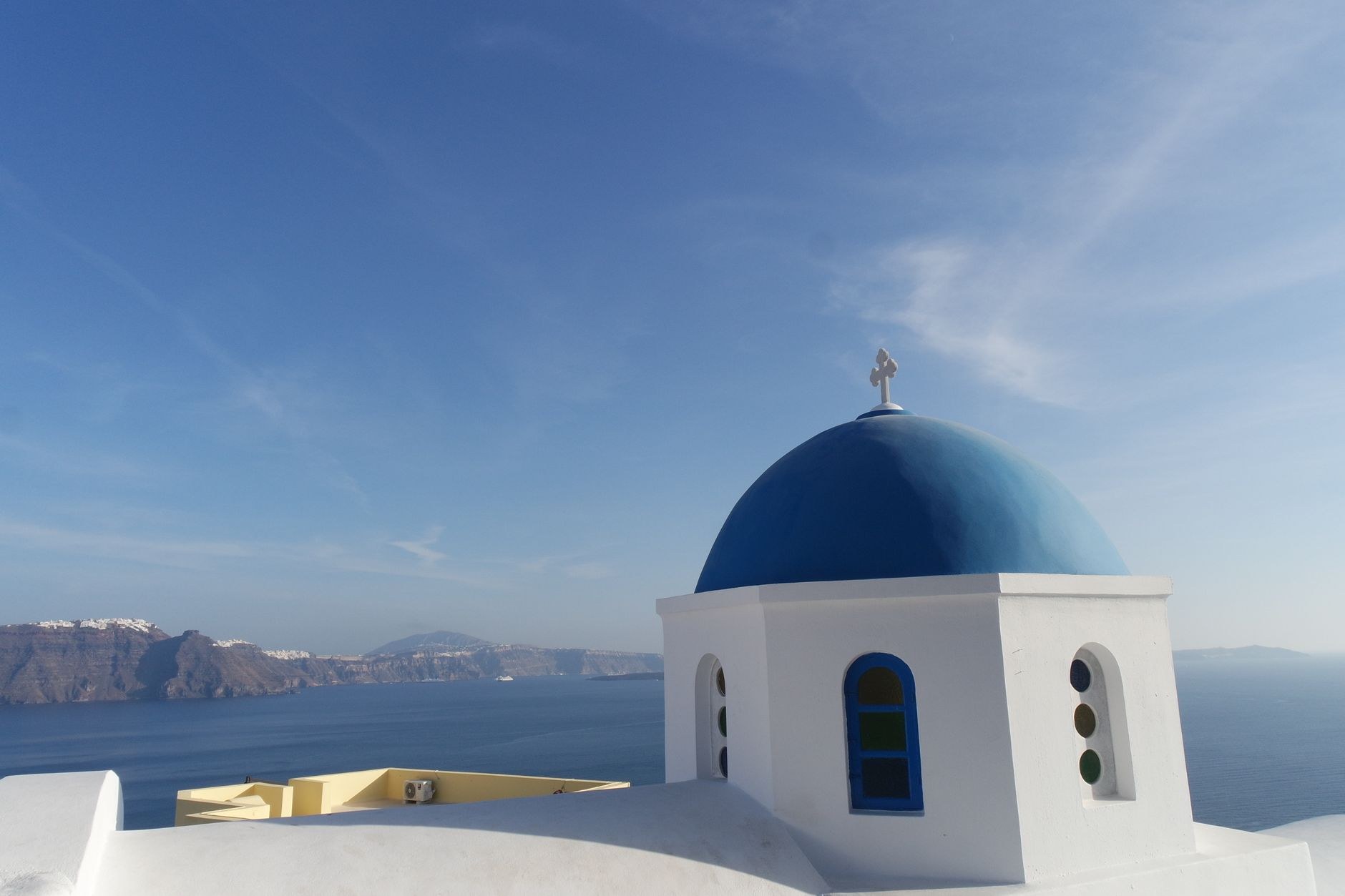Whitewashed houses and iconic blue-domed church overlooking the volcanic Santorini caldera