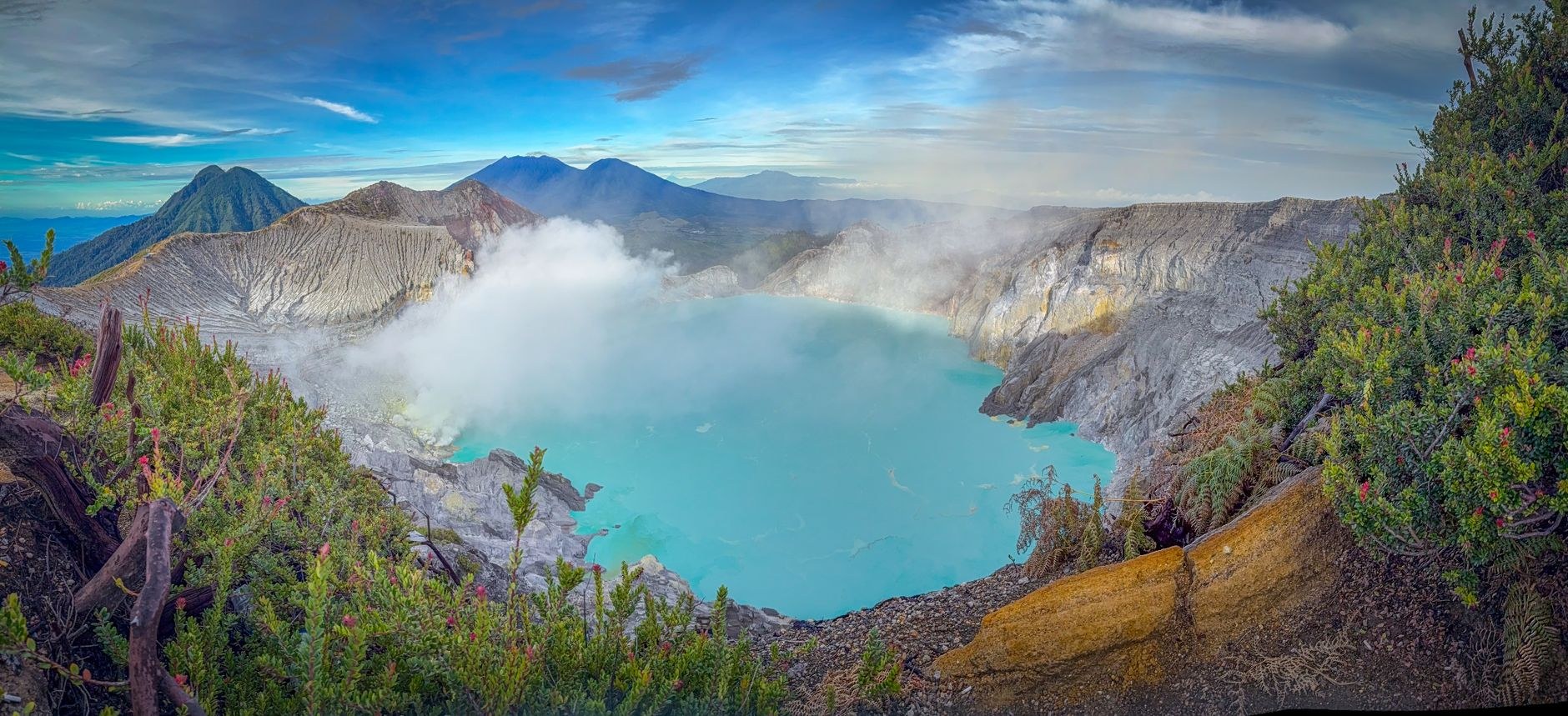 A deep volcanic crater lake encircled by dense tropical rainforest and mist-shrouded green peaks