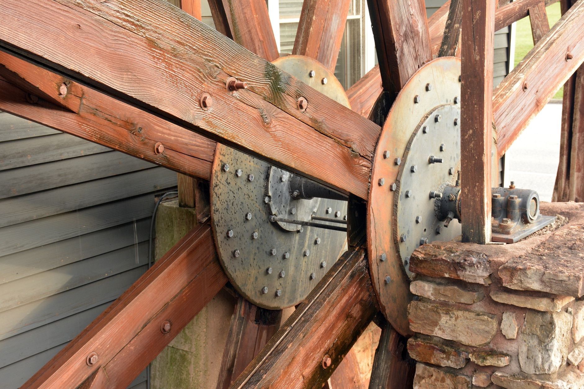 A monumental 18th-century cast-iron waterwheel turning slowly to power a rustic sugarcane press