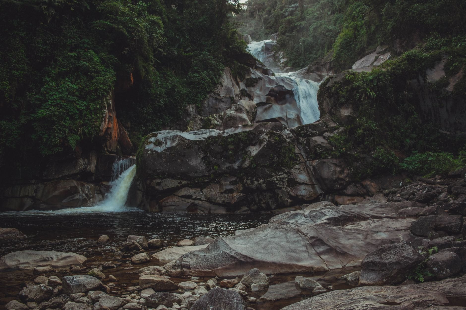Powerful forty-three-meter waterfall cascading down vertical limestone cliffs enveloped by lush rainforest vegetation