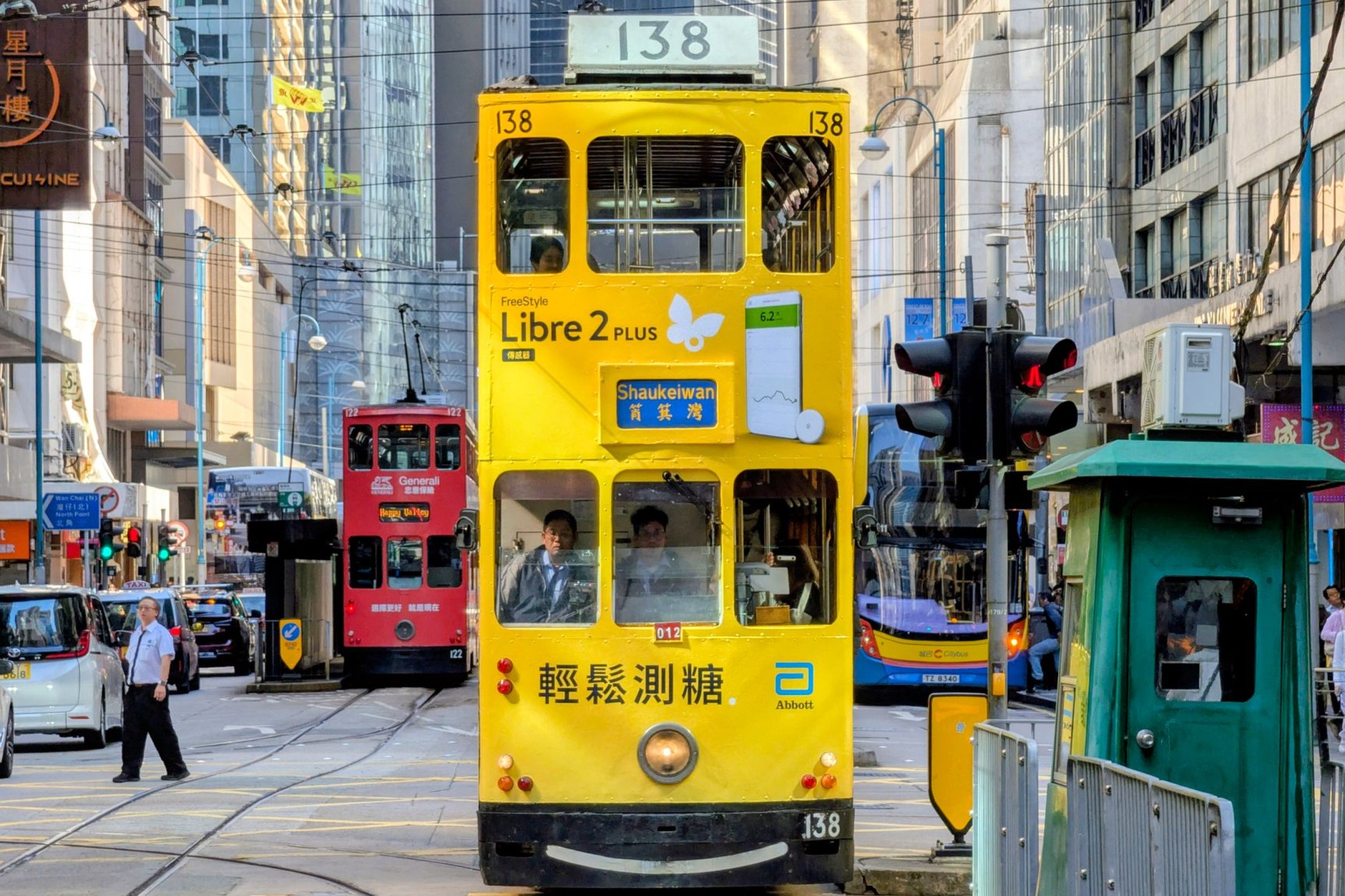 Classic double-decker Ding Ding tram rattling through bustling neon-lit commercial streets on Hong Kong Island