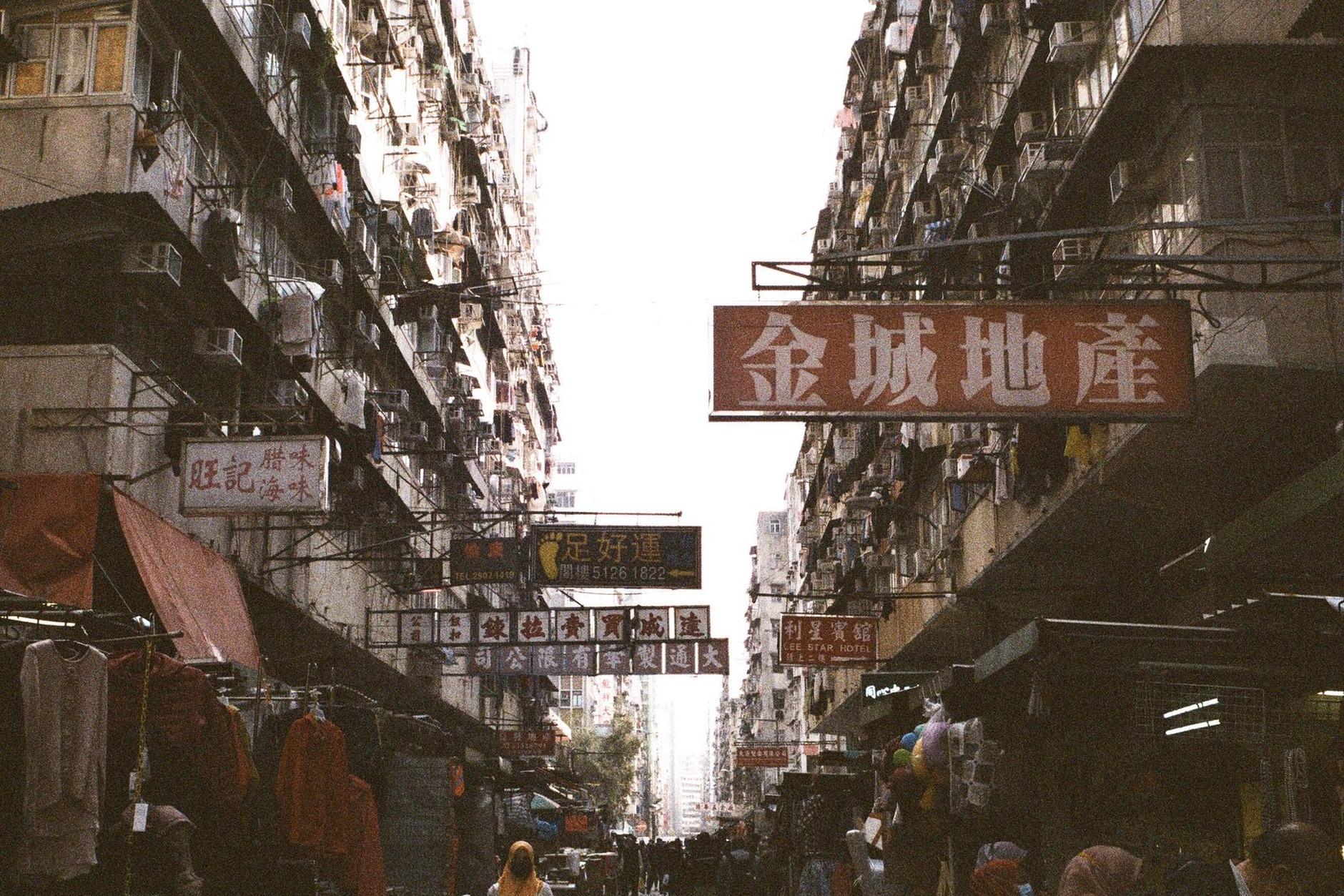 Bustling street stalls, electronic shops, and overhead neon signage in working-class Sham Shui Po Kowloon