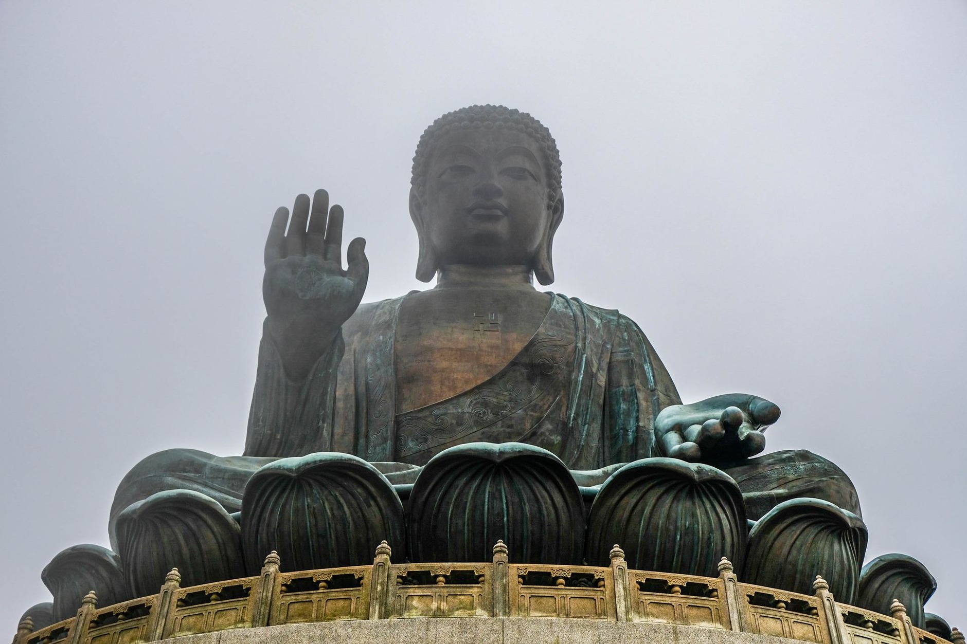 Majestic bronze statue of Tian Tan Big Buddha seated atop lotus throne on the lush mountain ridge of Lantau Island